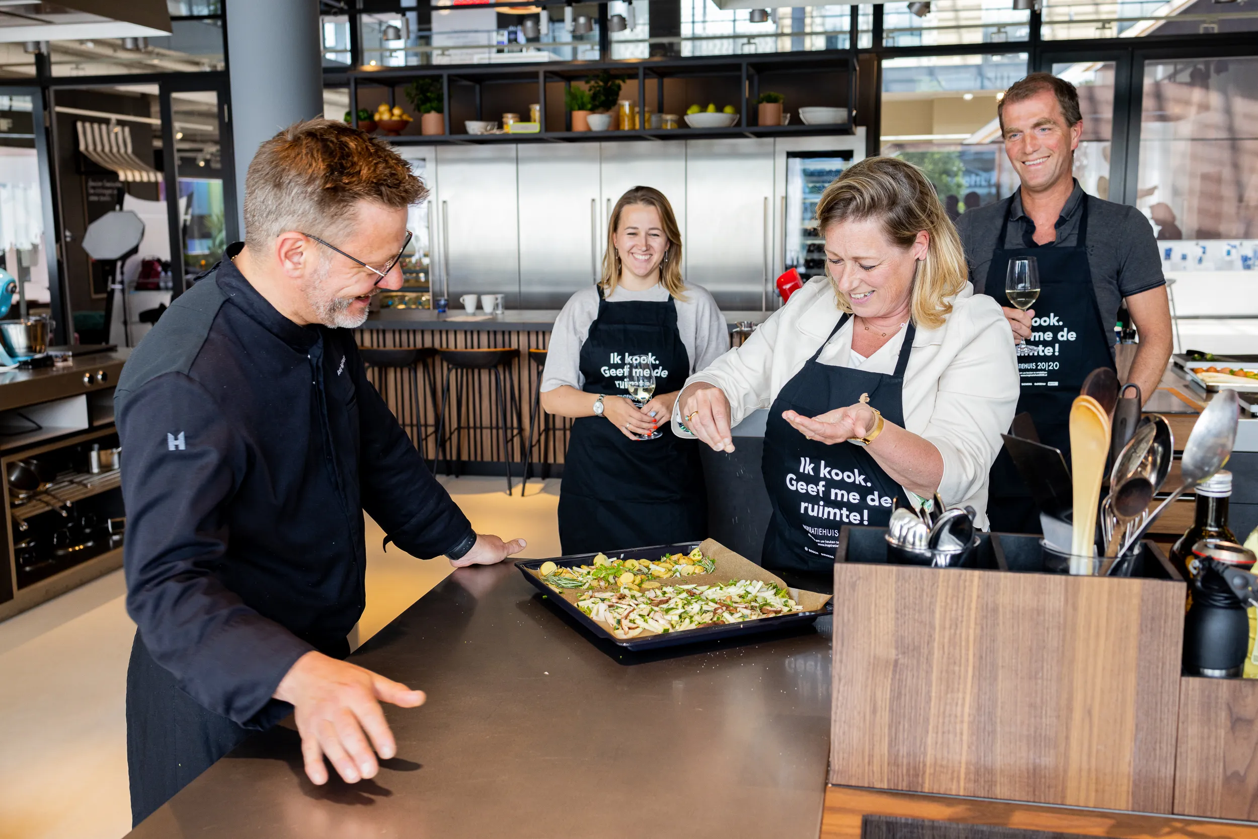 Vier mensen werken samen in een keuken, bereiden eten op een grote schaal.