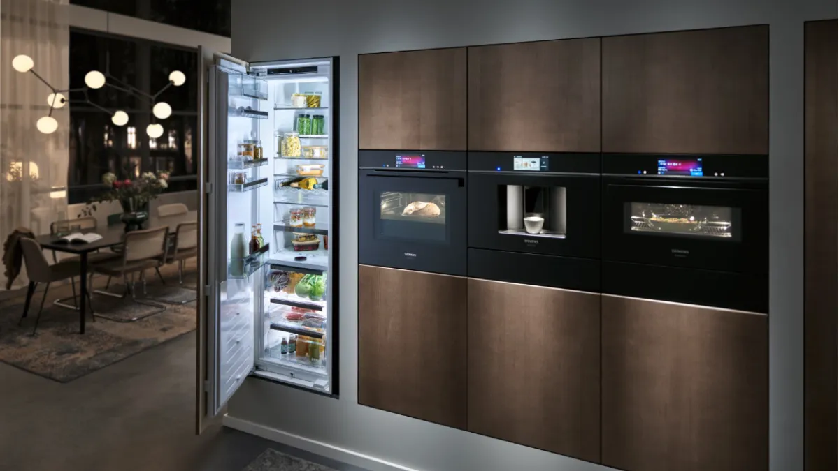 Cozinha moderna com armários escuros, eletrodomésticos embutidos e um refrigerador de porta de vidro.