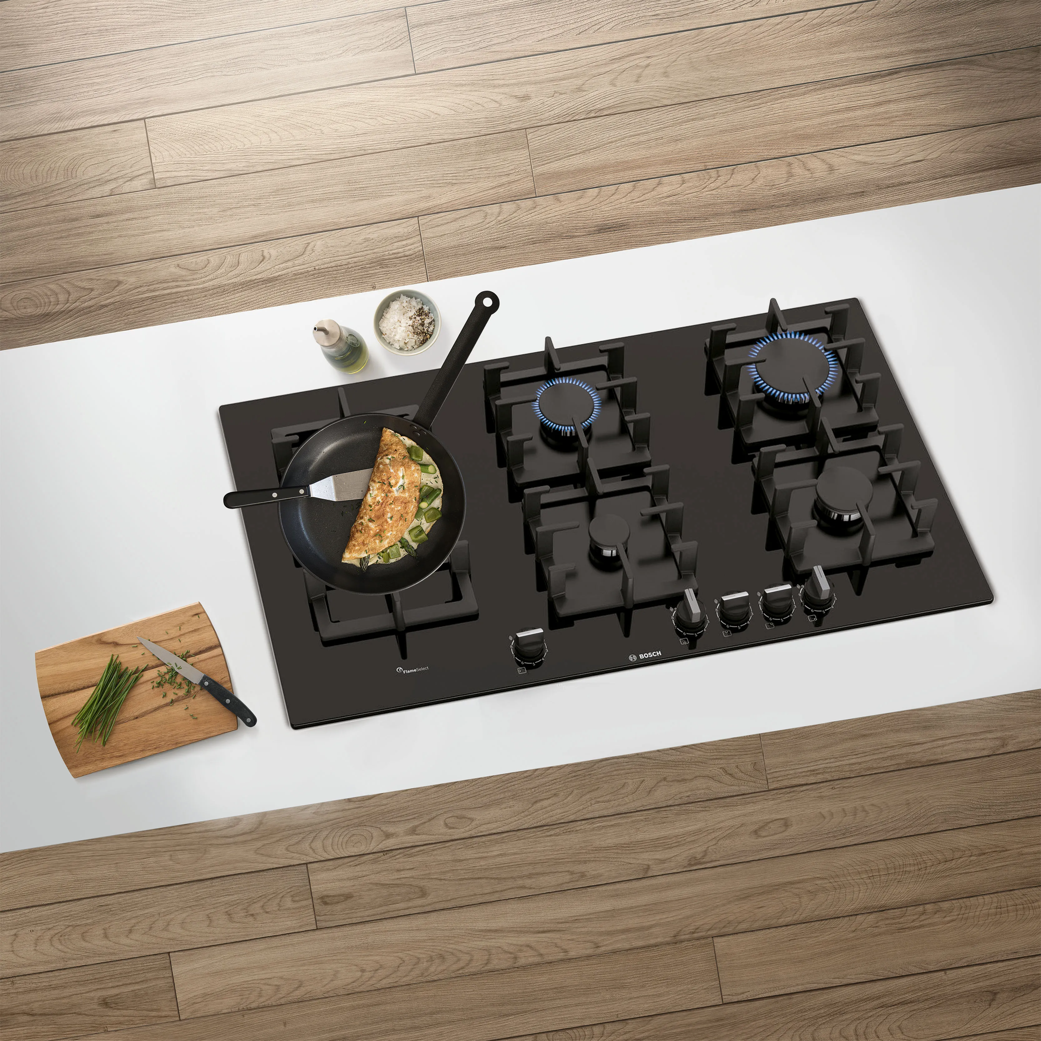 כיריים חסונות של בוש עם מחבת מלאה באומלט ירוק, על משטח עבודה לבן עץ כהה. סמלים כחולים מסמנים חום גבוה.