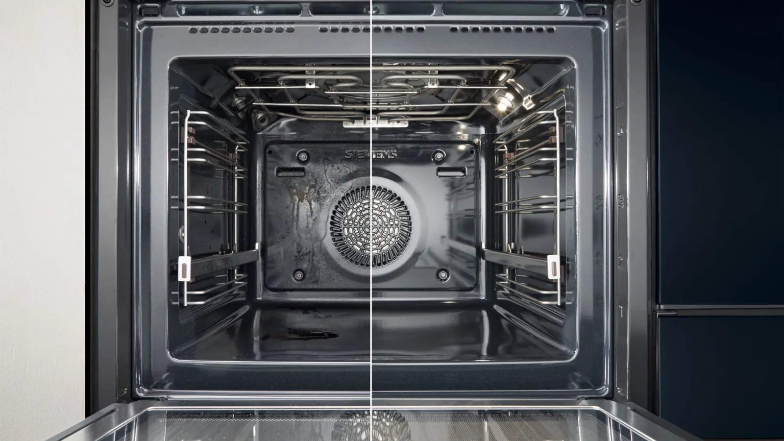 Interieur van een moderne oven met roestvrijstalen rekken, een ronde ventilator en een strakke zwarte afwerking.