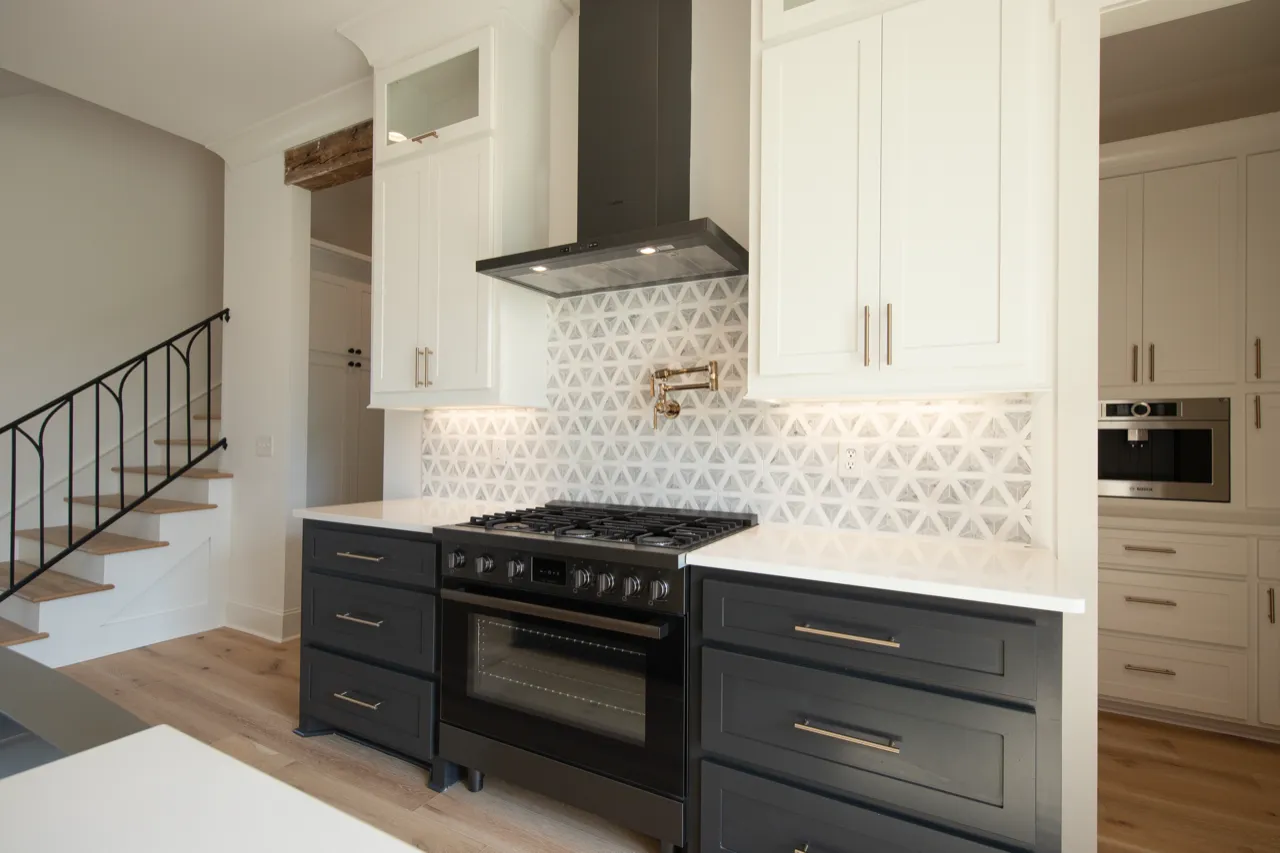Modern kitchen with Bosch black stove and geometric backsplash, white cabinets, and wood floor.