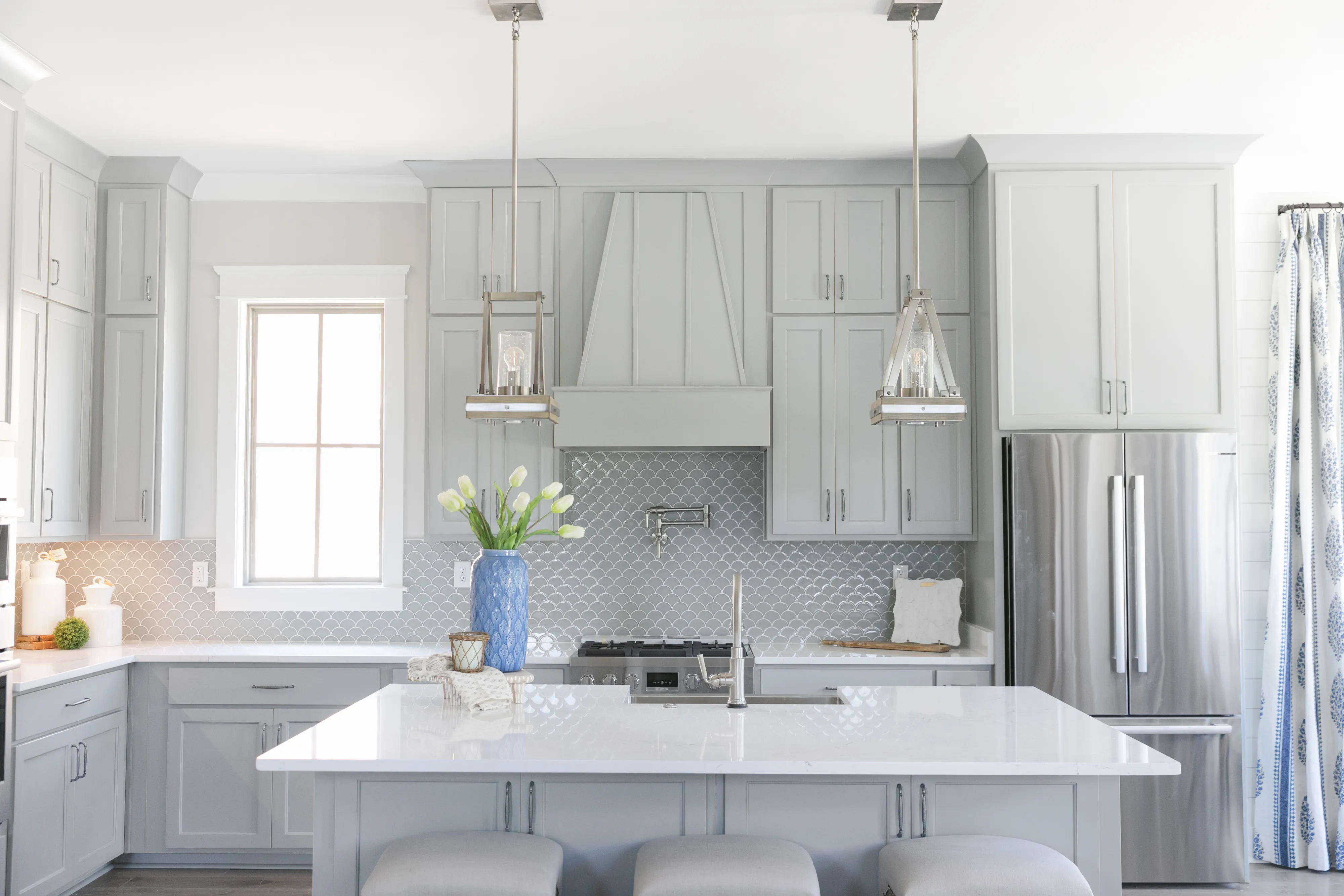 Modern kitchen with Bosch appliances, gray cabinets, pendant lights, and a large island with seating.