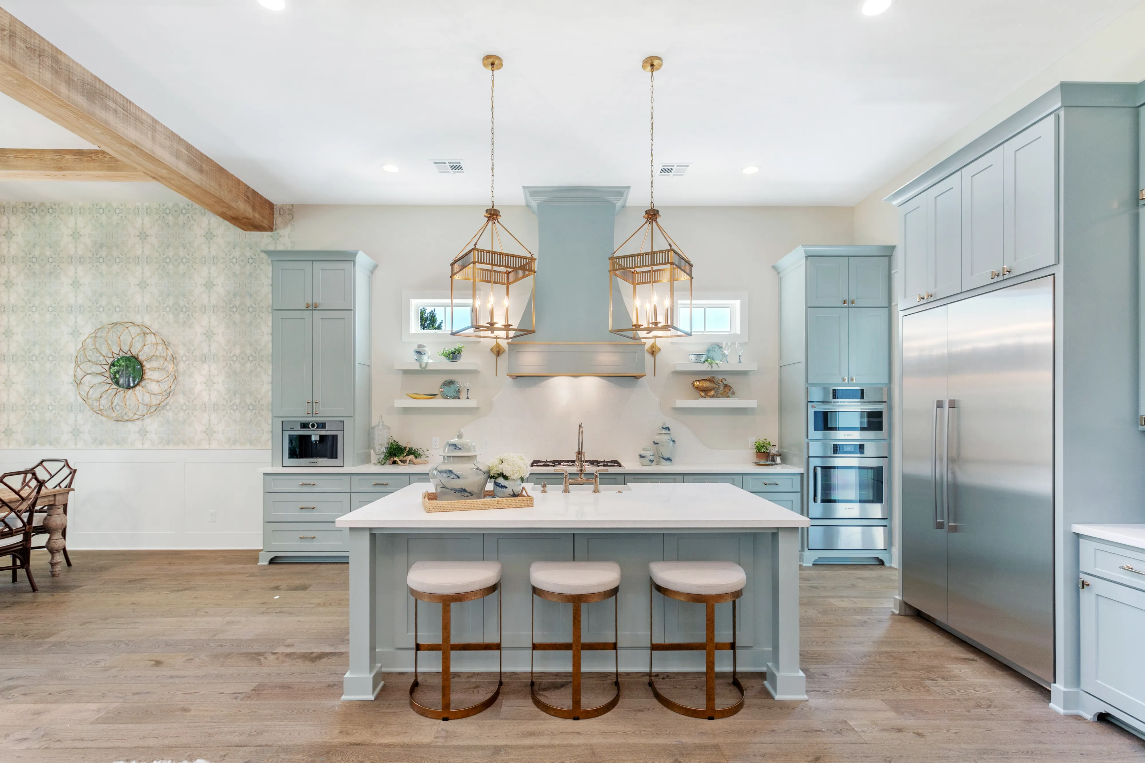 Modern kitchen with a Bosch appliances, large island, stools, and hanging lights in a spacious, bright setting.