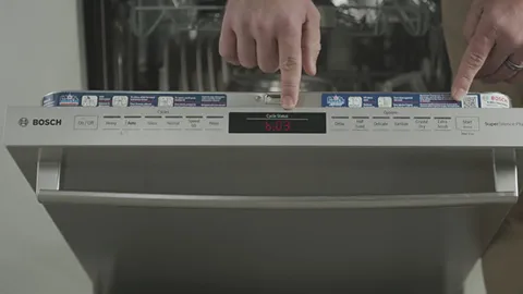 Hands operating controls of a Bosch dishwasher with digital display.
