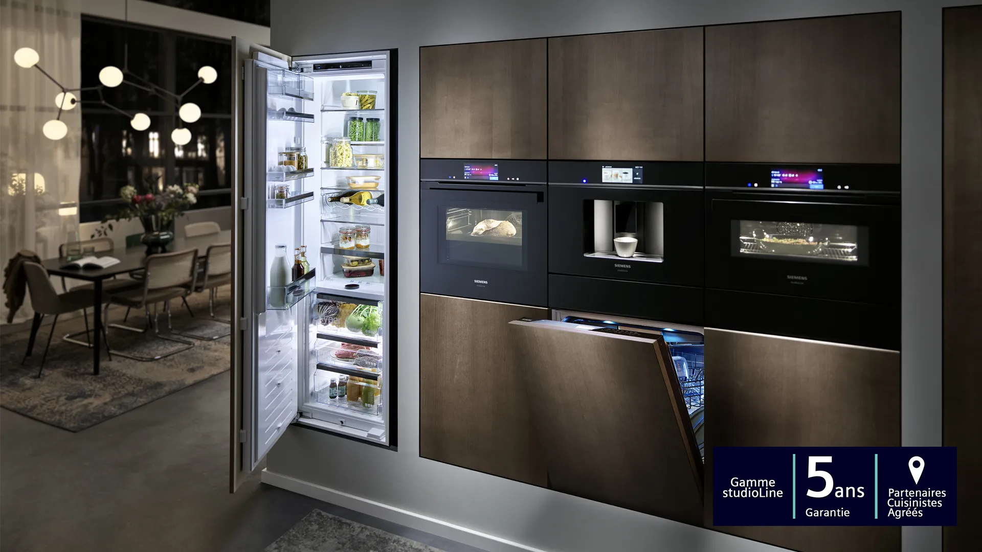 Cuisine moderne avec armoires noires élégantes, réfrigérateur ouvert, et divers appareils de cuisine.
