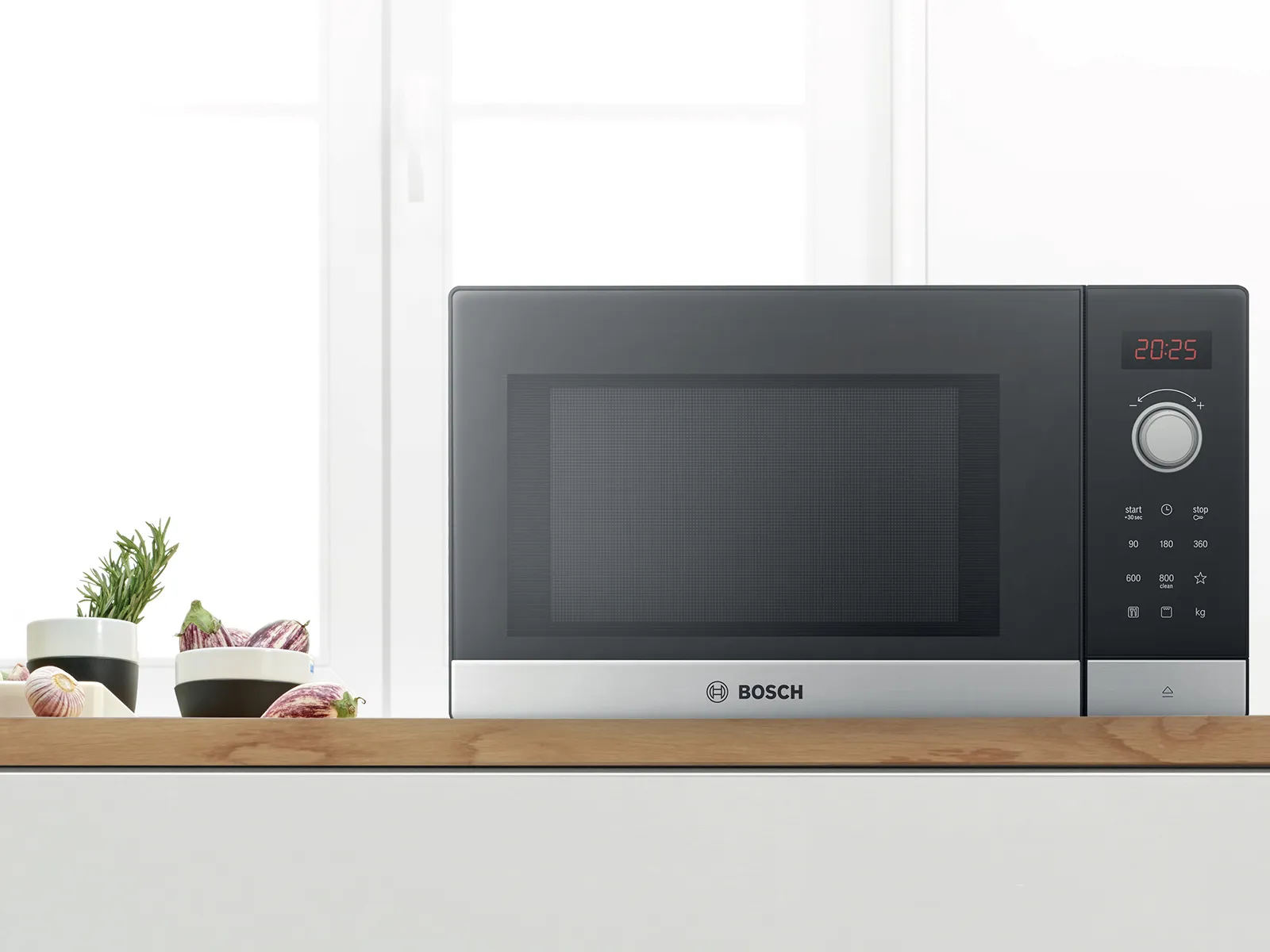 Freestanding microwave sitting on a kitchen counter, with ingredients and vegetables.