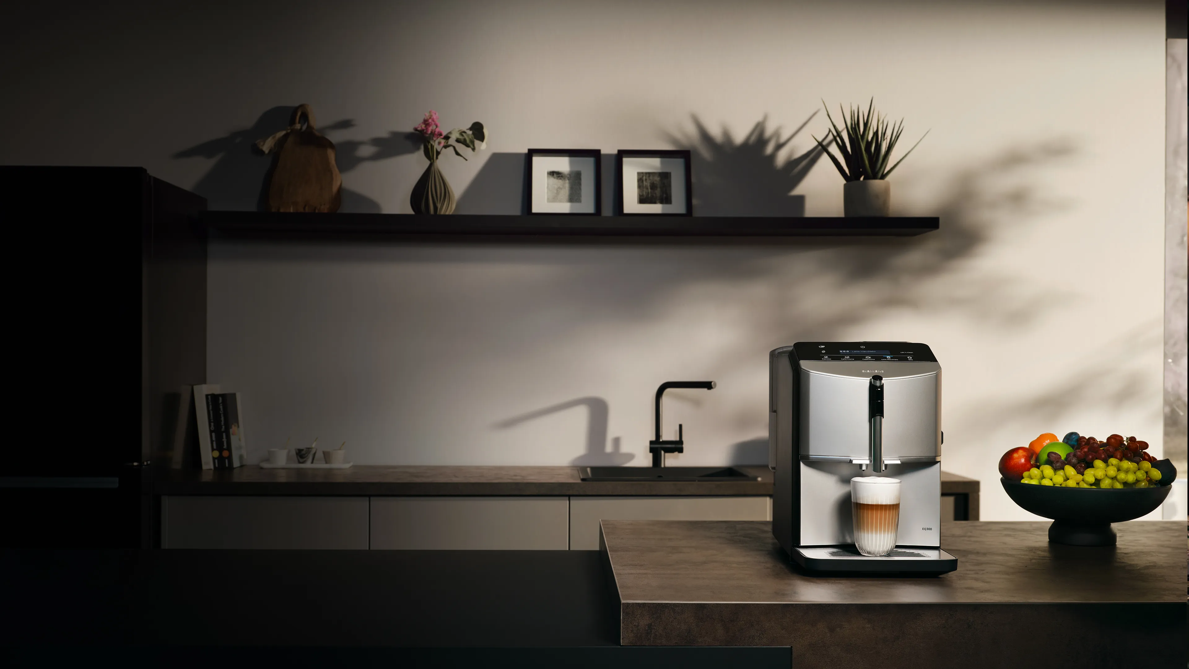 Kitchen with EQ300 fully automatic espresso machine on the kitchen island, a glass of latte macchiato is under the outlet.