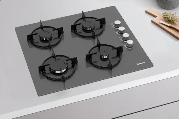 Four-burner gazı, mutfak aletleri ile beyaz yüzeyde pişirilir.