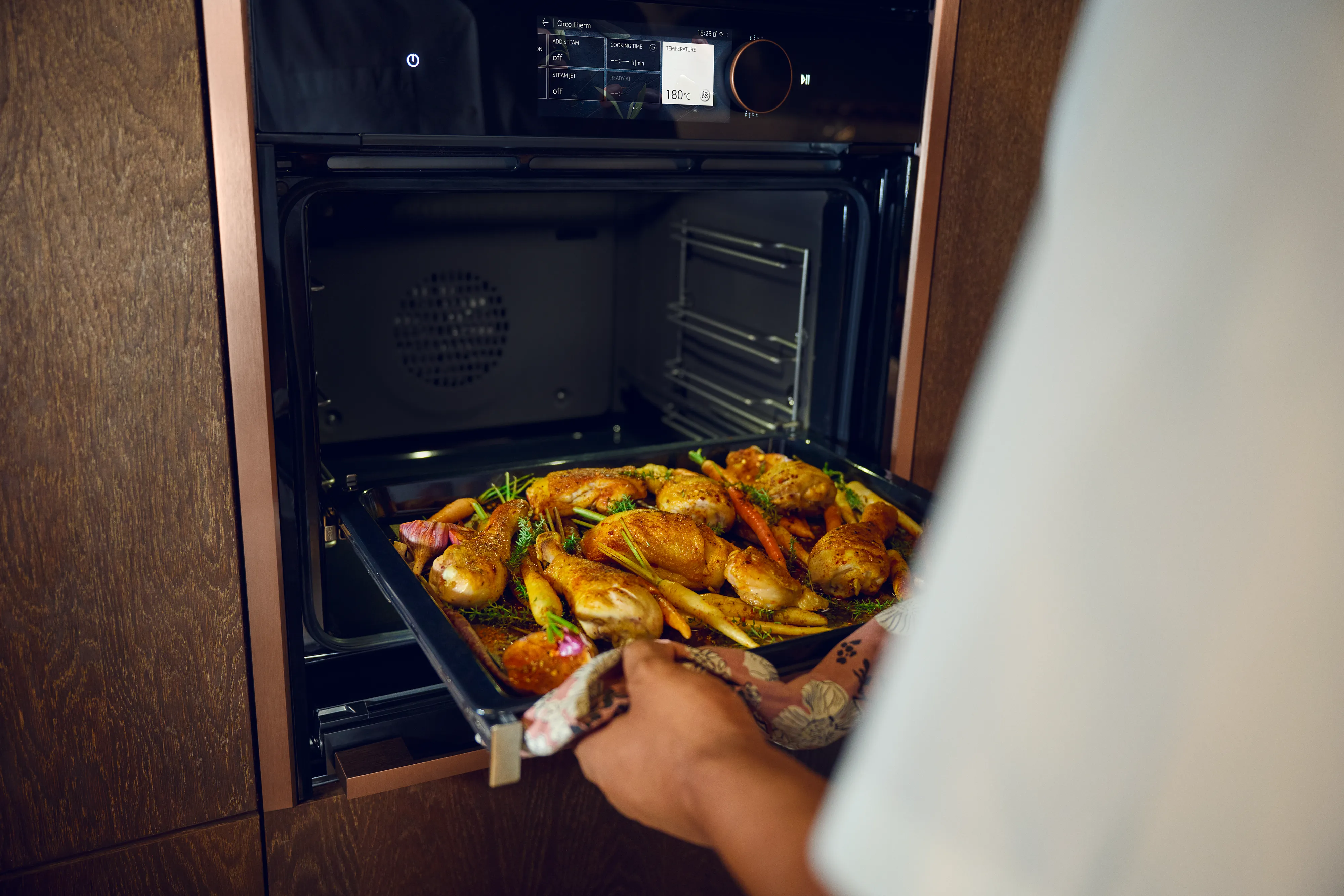 Blech mit Hähnchen wird in einen NEFF Backofen geschoben