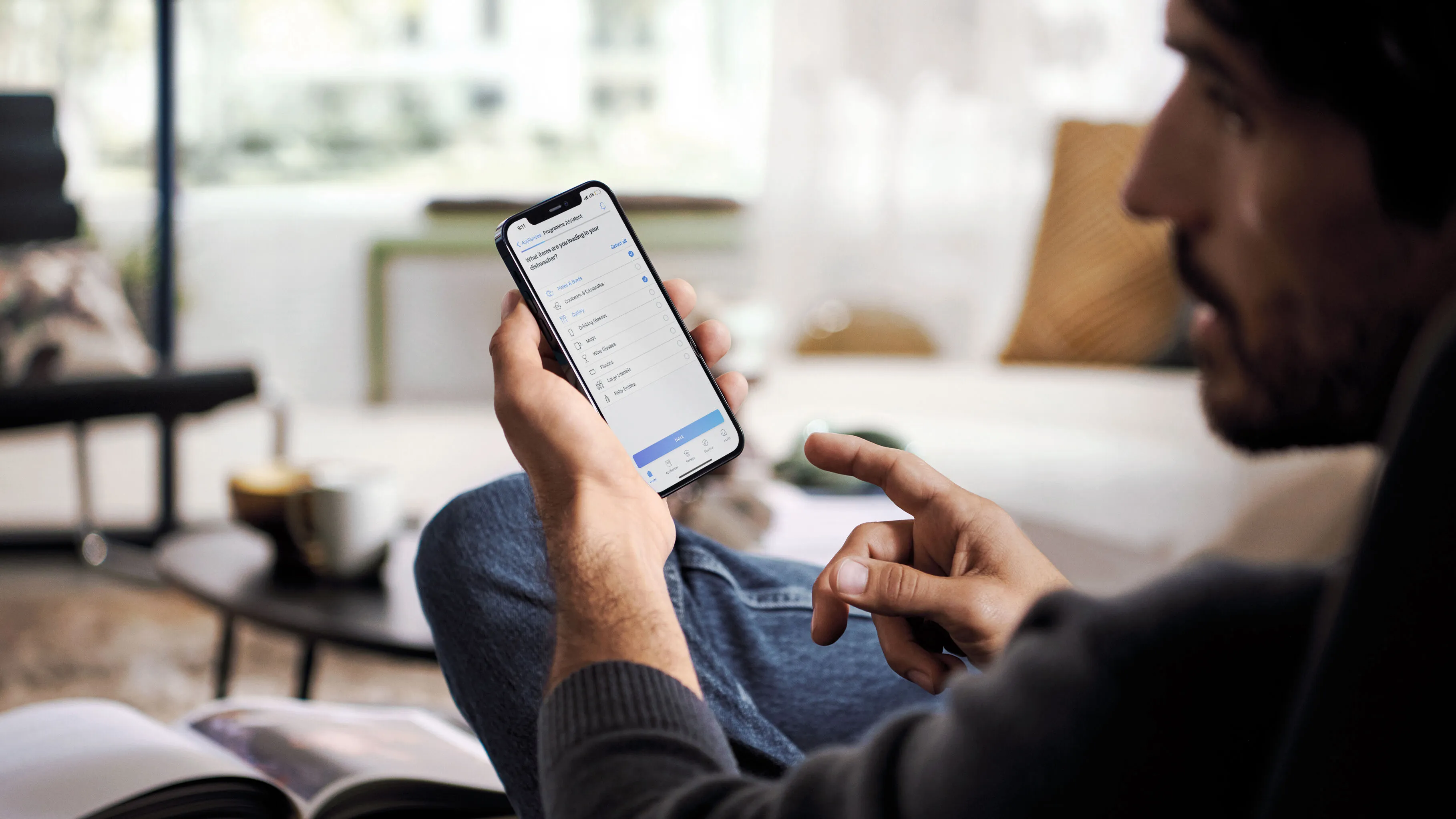 Muž pomocí smartphonu v útulné domácí prostředí, relaxaci na pohovce.