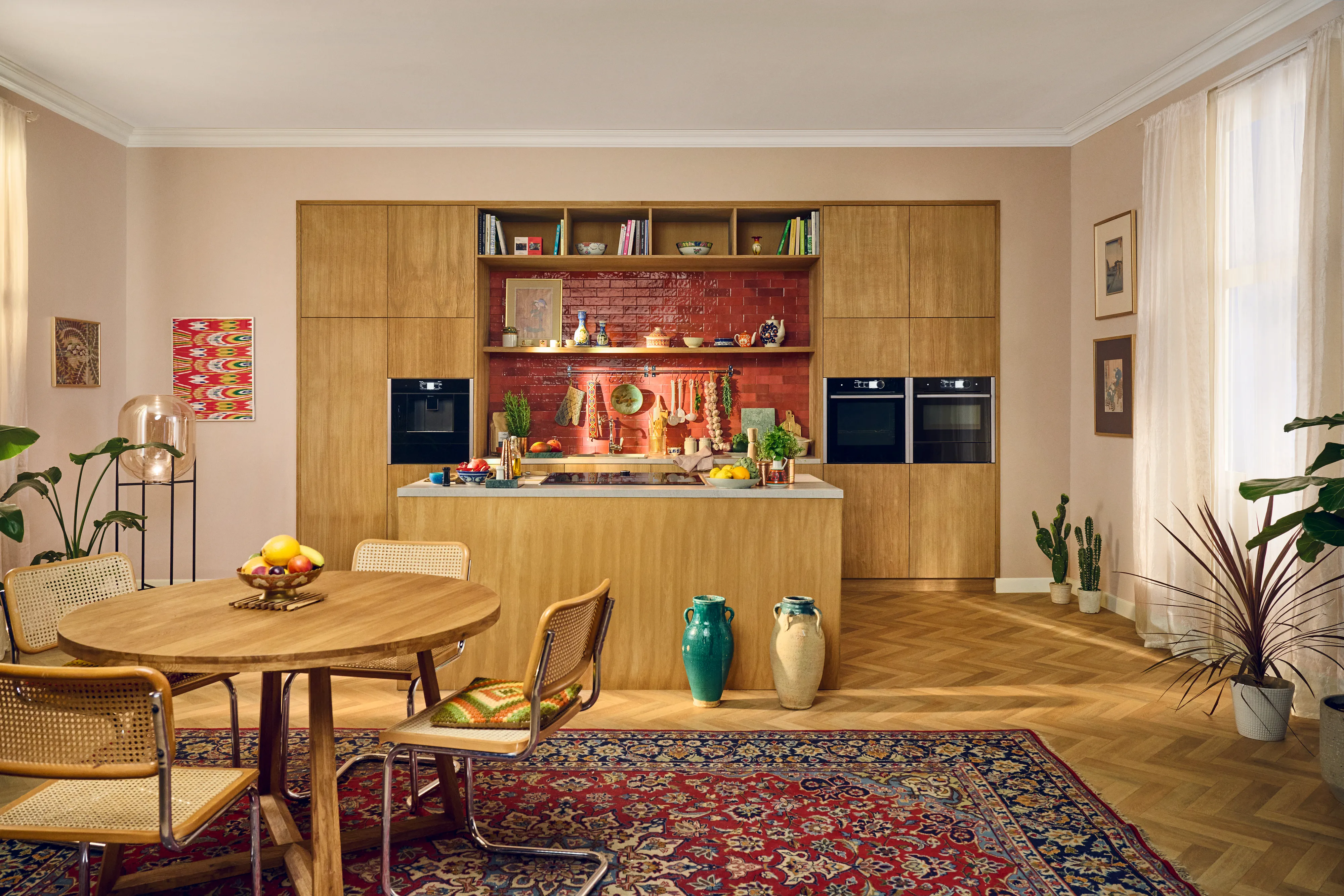 Ampia cucina-sala da pranzo con armadi in legno, arredamento colorato, e un grande tavolo da pranzo rotondo.