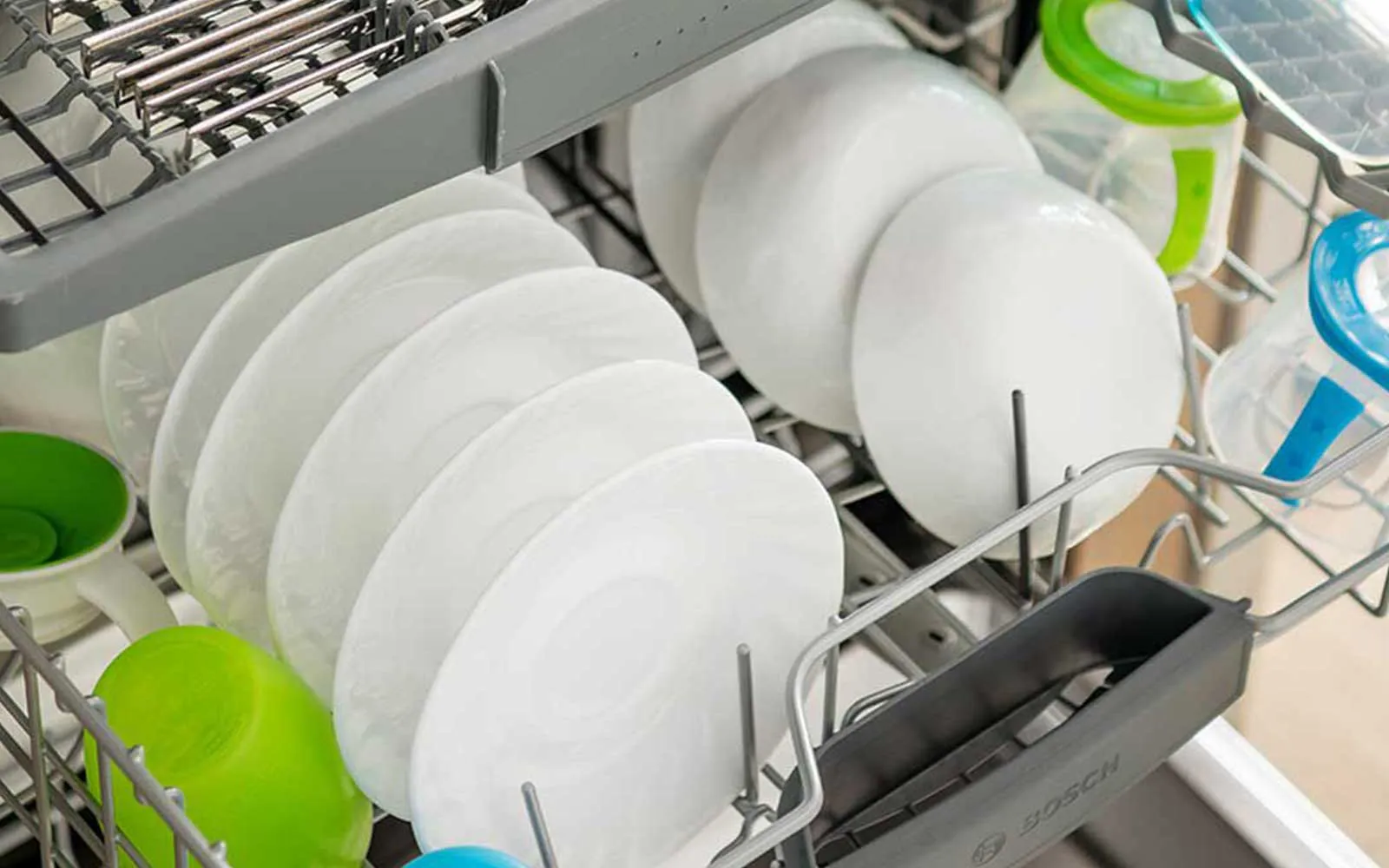 Intérieur lave-vaisselle avec assiettes blanches et bols propres, prêts à être stockés.