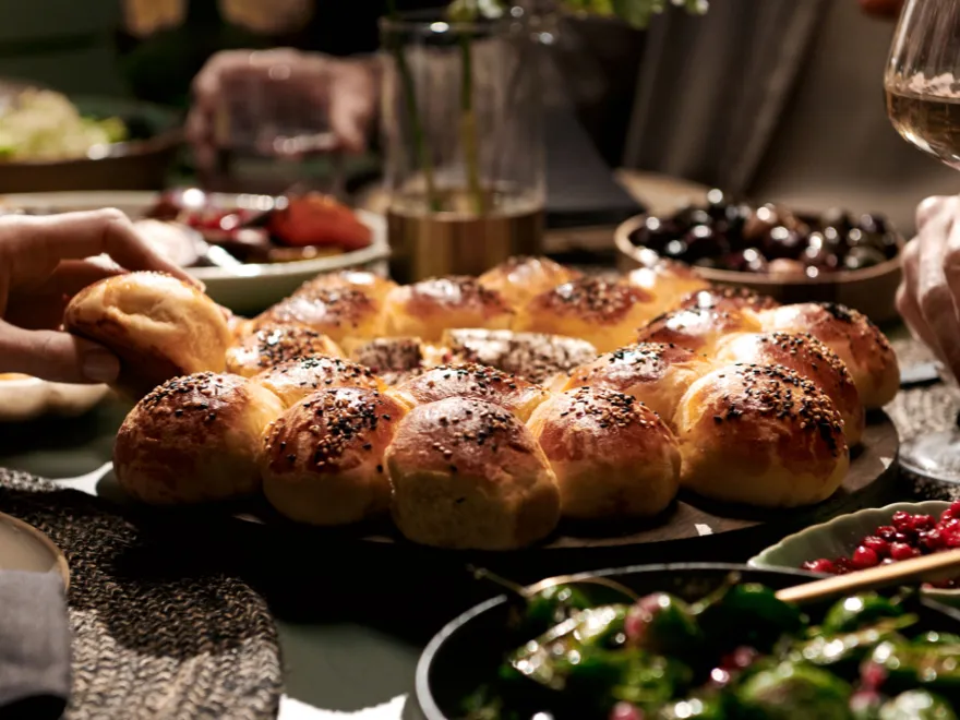 Freshly baked challah bread, olives, and wine on a rustic table setting.