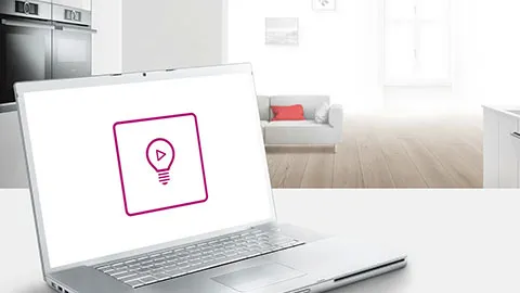 Laptop displaying a video tutorial icon on screen in a bright modern home interior.
