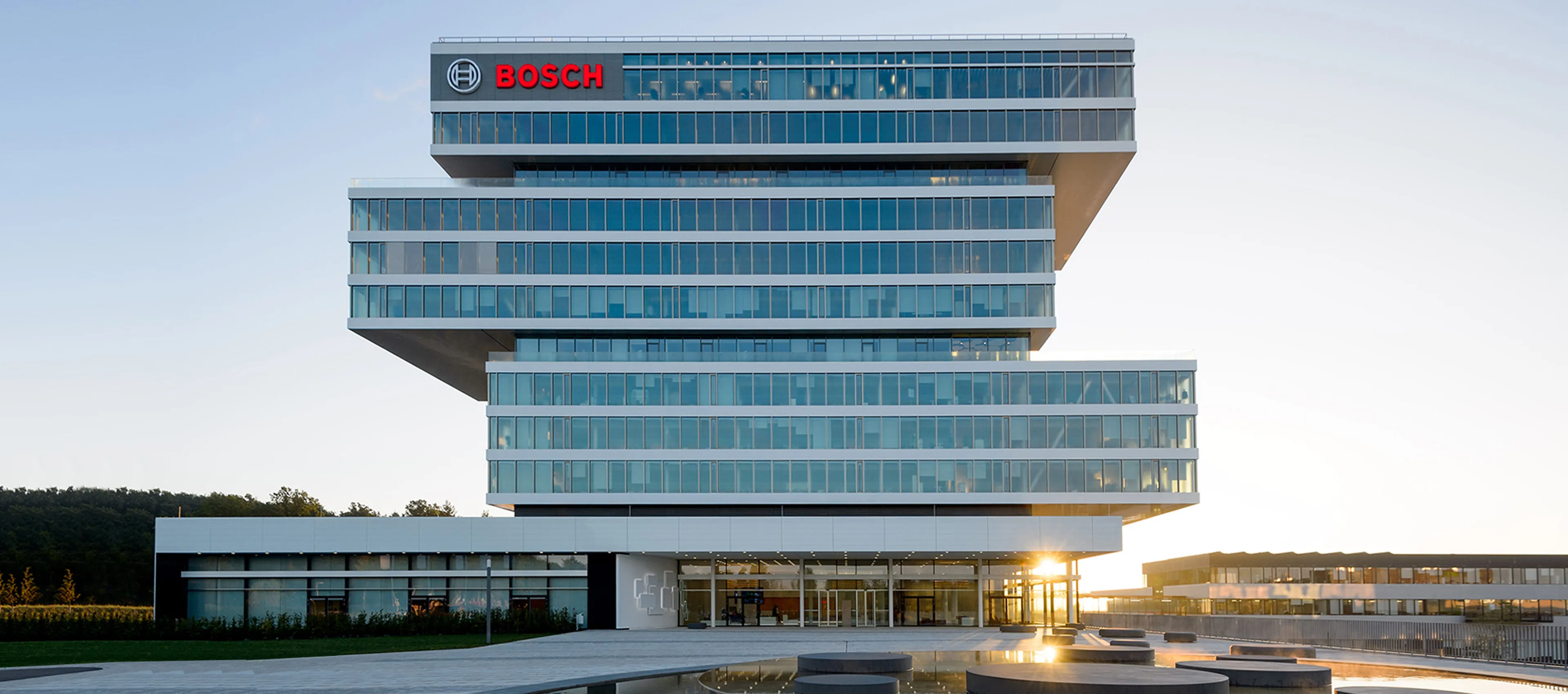 Das moderne Hauptgebäude des Bosch-Forschungscampus in Renningen mit einer markanten Architektur aus versetzt gestapelten, gläsernen Etagenblöcken unter klarem Himmel.