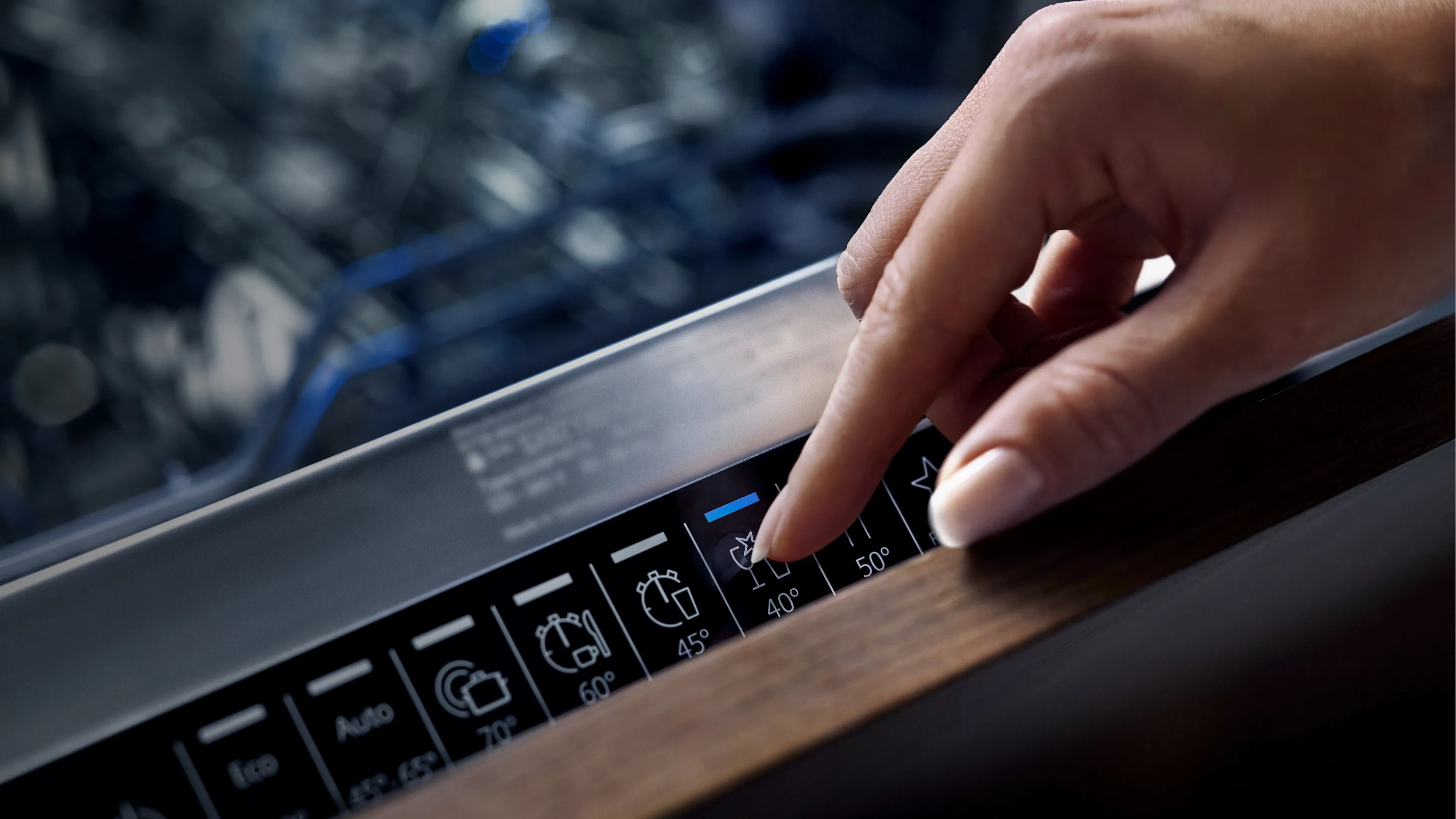 Nahaufnahme einer Hand, die eine Taste auf einem Spülmaschinen-Panel drückt und das 40°C-Programm für Empfindliches wählt.