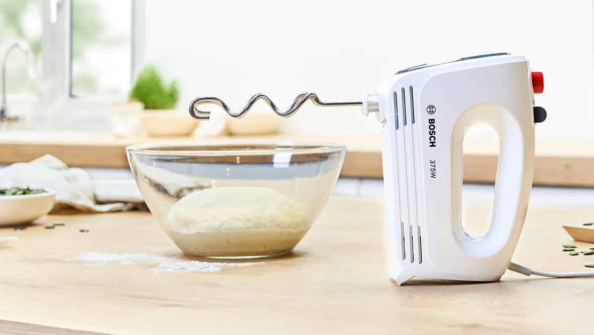 CleverMixx hand mixer with dough hook attachment, effortlessly kneading dough in a glass bowl for homemade baking perfection.