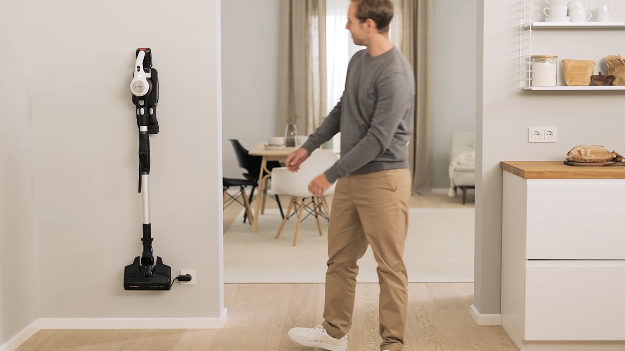 Modern, minimalist bir ev içinde elektrikli süpürgeyi kullanan adam.