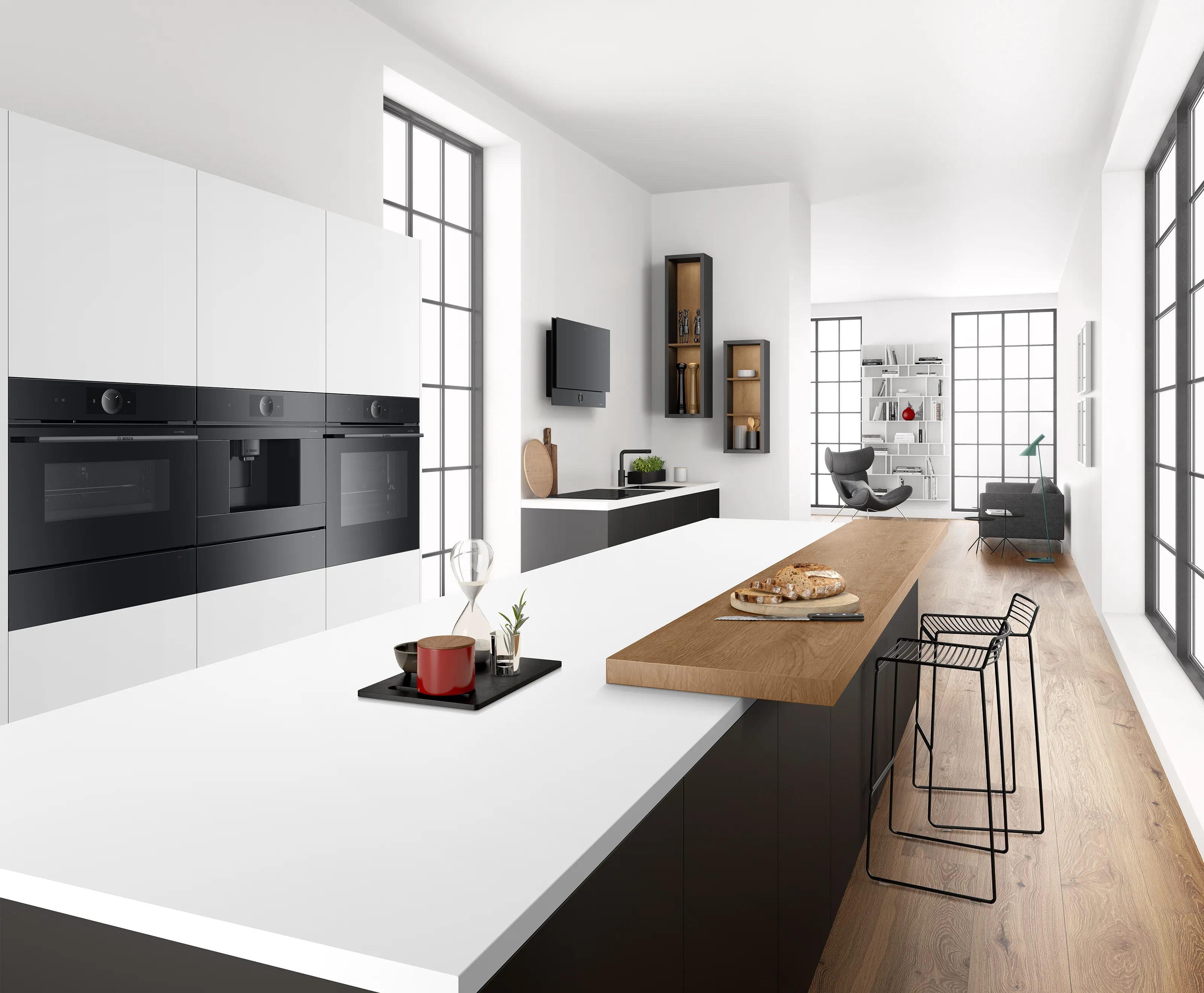 Moderne Loft-Küche in Weiß und Schwarz mit großer Kücheninsel, Holztheke und nahtlos eingebauten, schwarzen Backöfen in der Schrankwand.