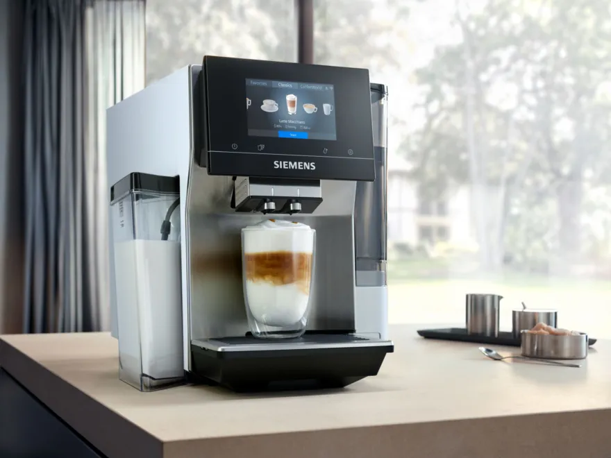 Coffee machine on wooden table with cups and accessories.