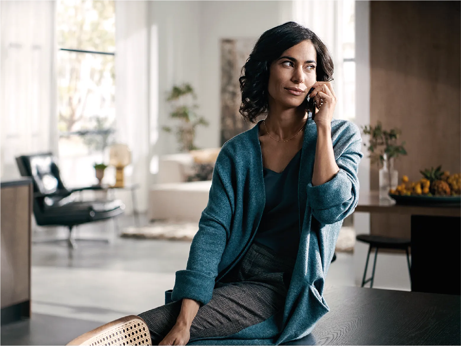 A woman sitting on a table, engaged in a conversation on her phone.