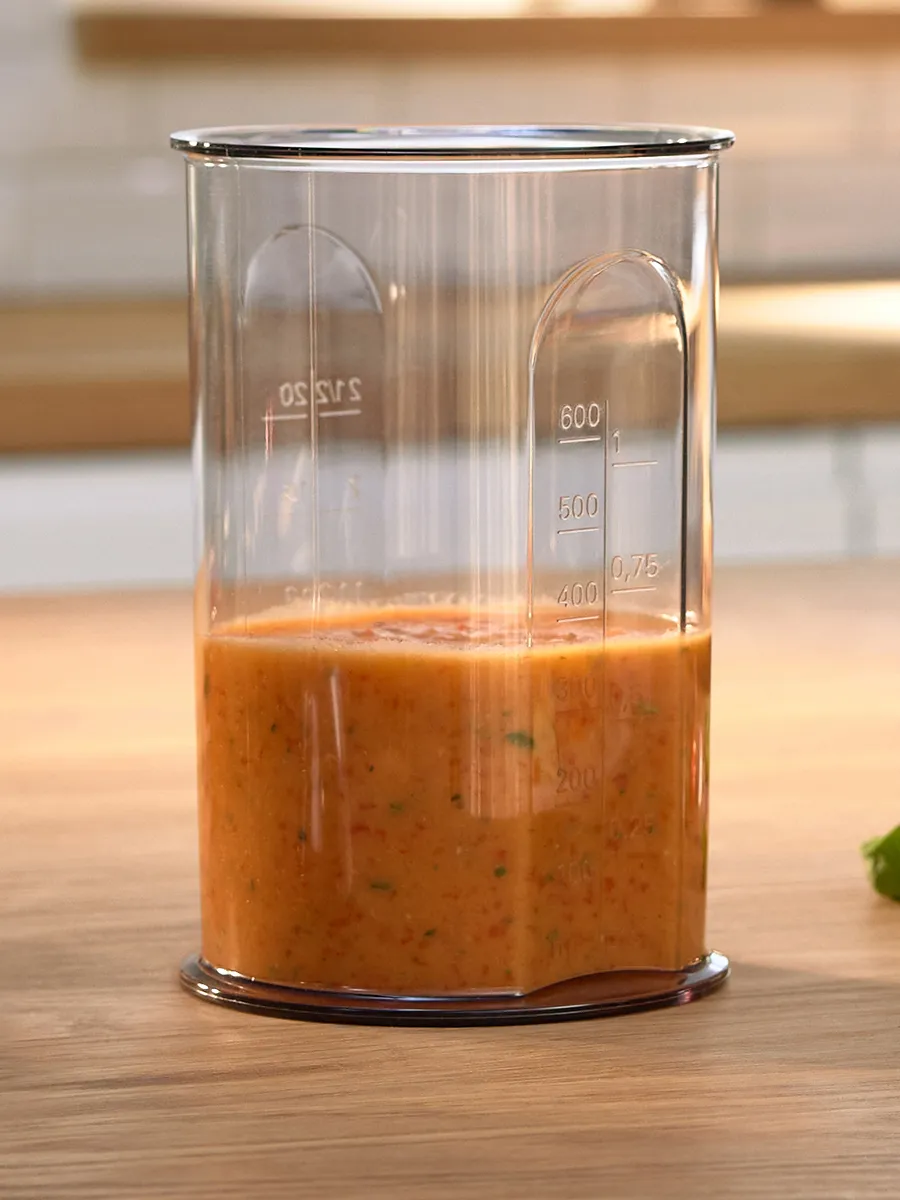 Transparent measuring beaker with clear markings, filled with freshly blended sauce. Perfect for precise mixing and measuring.