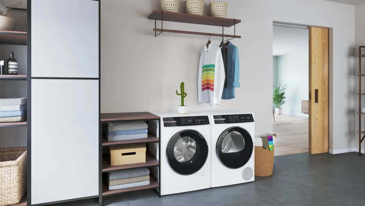 Een wasserette met een kledingrek met hangende hemden en een paar witte wasmachine en droger.