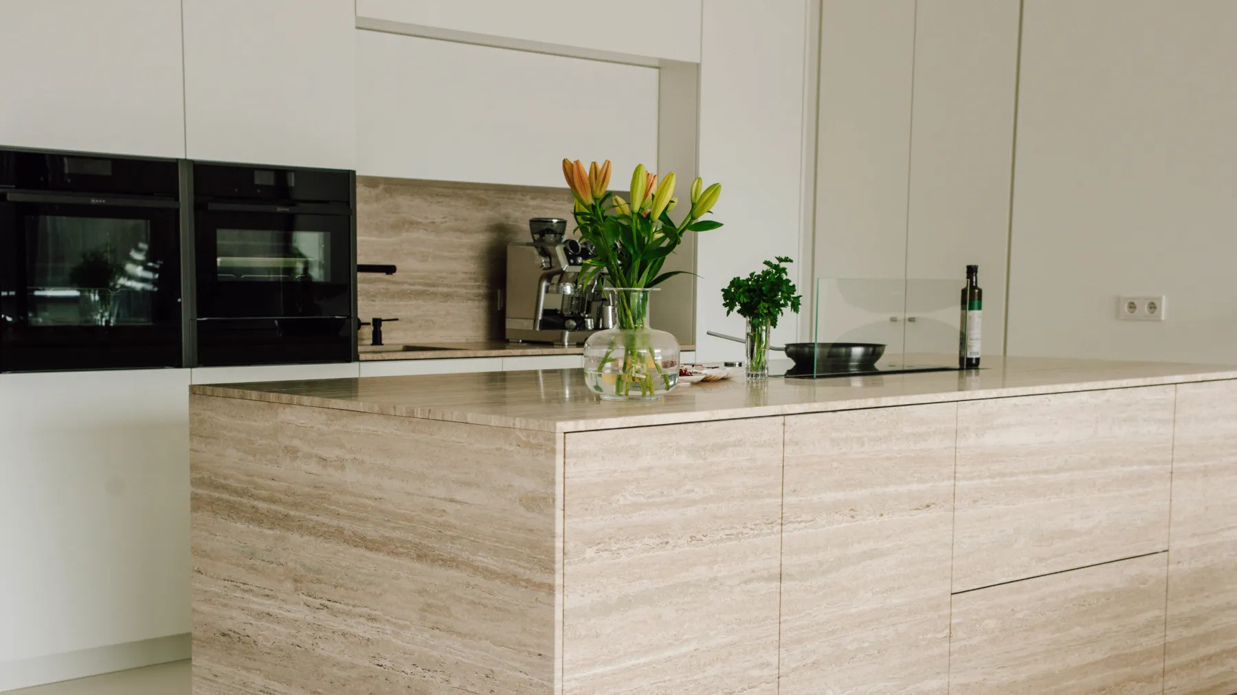 Moderne Küche mit Holzschränken, Geräten und floralen Dekor auf der Arbeitsplatte.