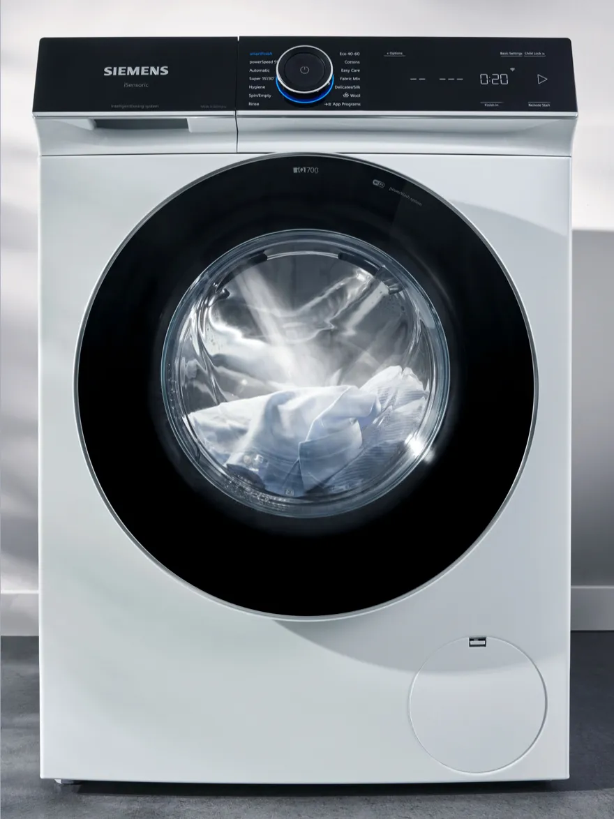 Siemens washing machine with digital display and open door showing clothes inside.
