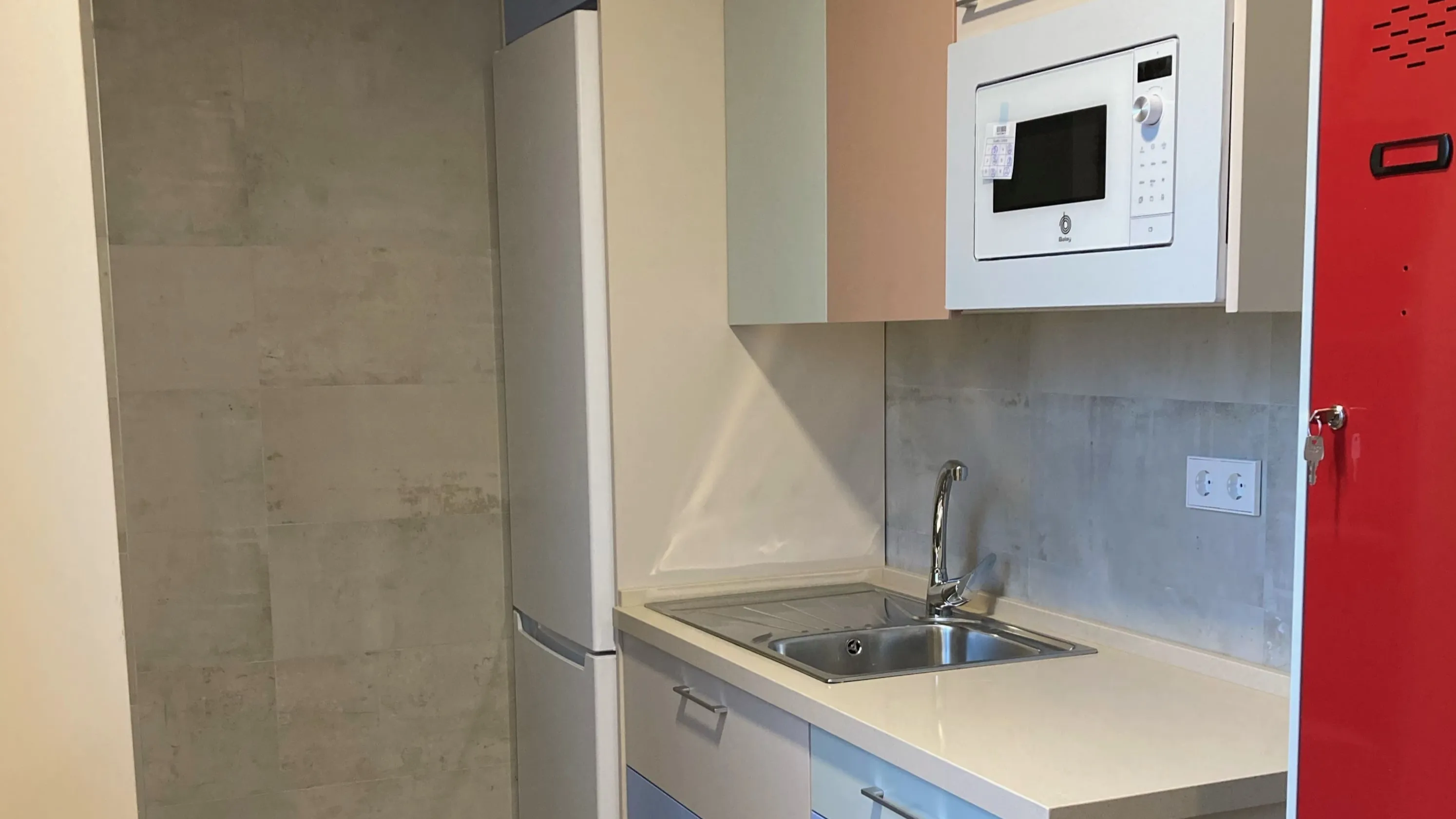 Cocina compacta con frigorífico, microondas y fregadero de diseño moderno y minimalista. 