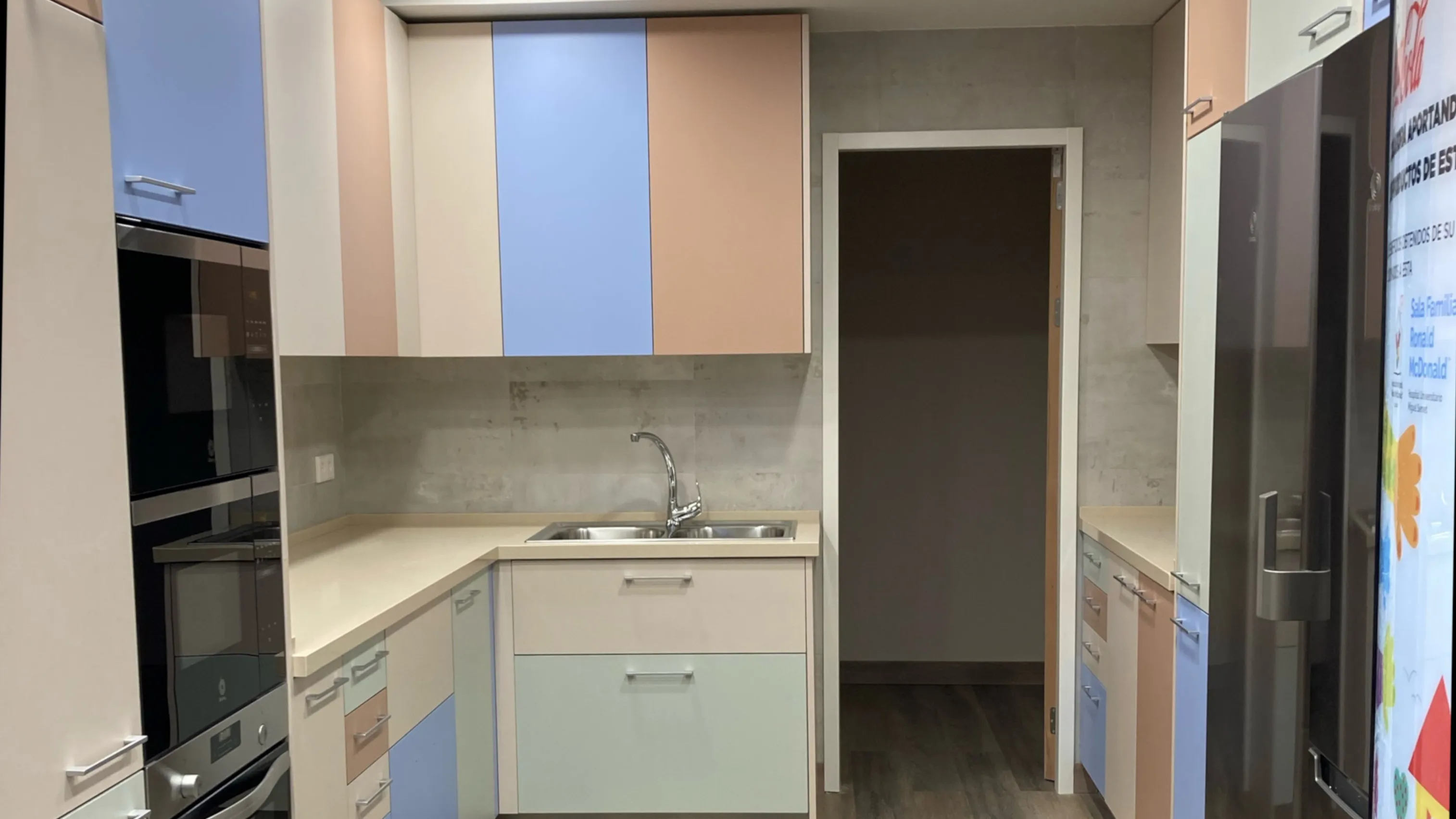 Cocina de hogar con muebles de colores y electrodomésticos de acero inoxidable. 