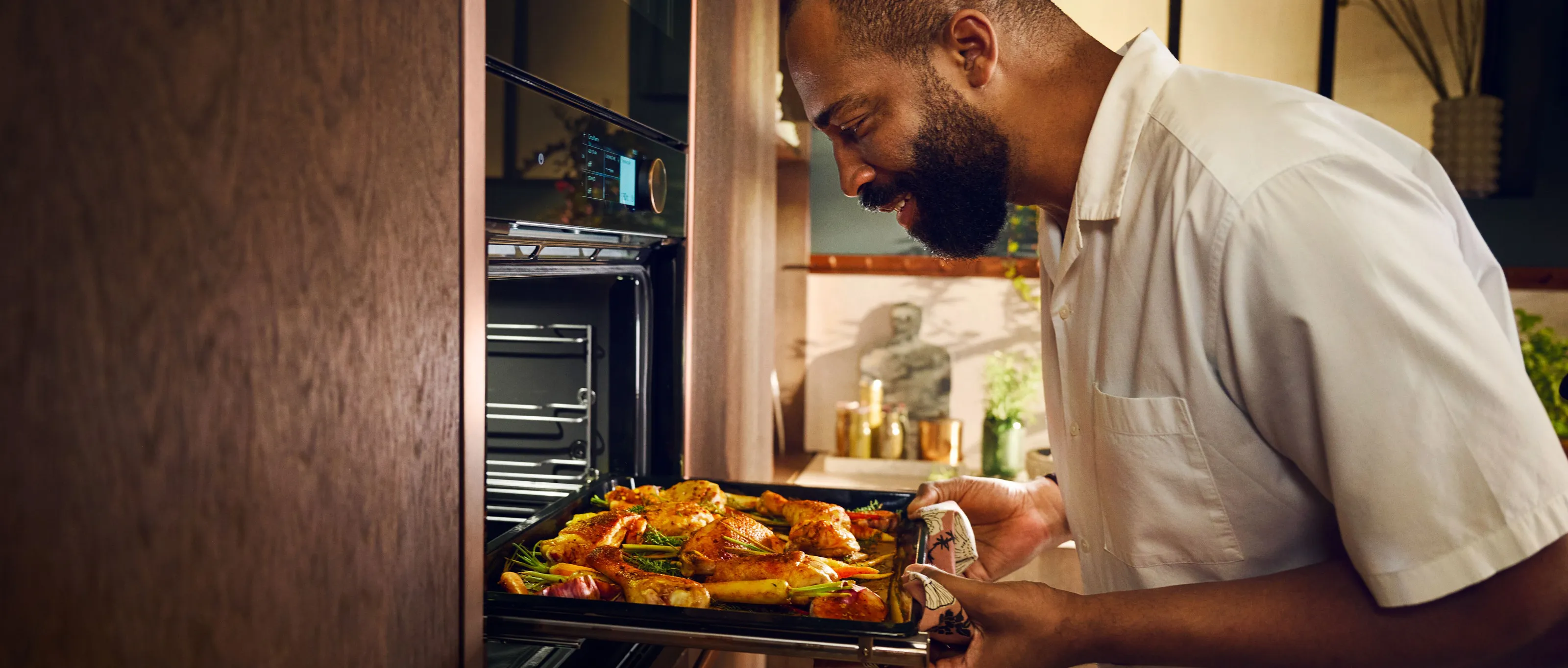 Dampffunktion von NEFF: Mann zieht belegtes Backblech aus Dampfbackofen