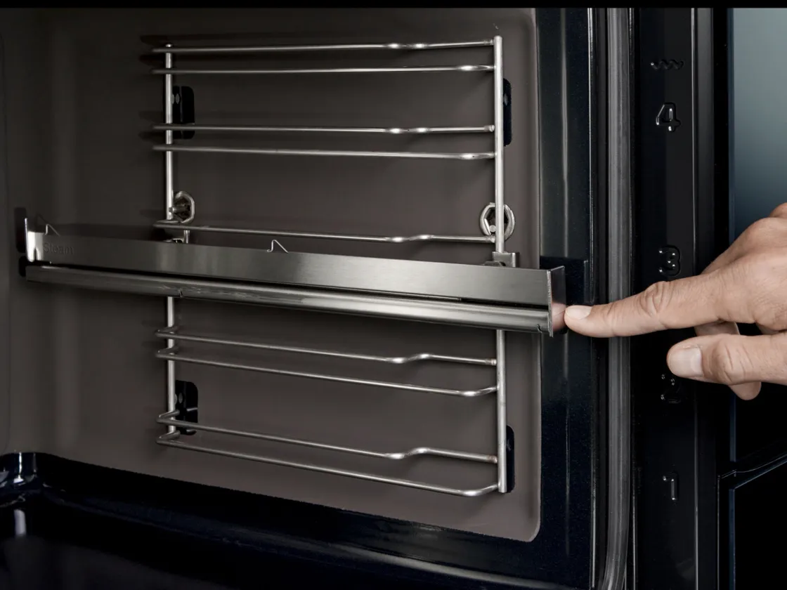 Interno del forno con porta scorrevole, porta del forno aperta e una mano che tocca le guide telescopiche.
