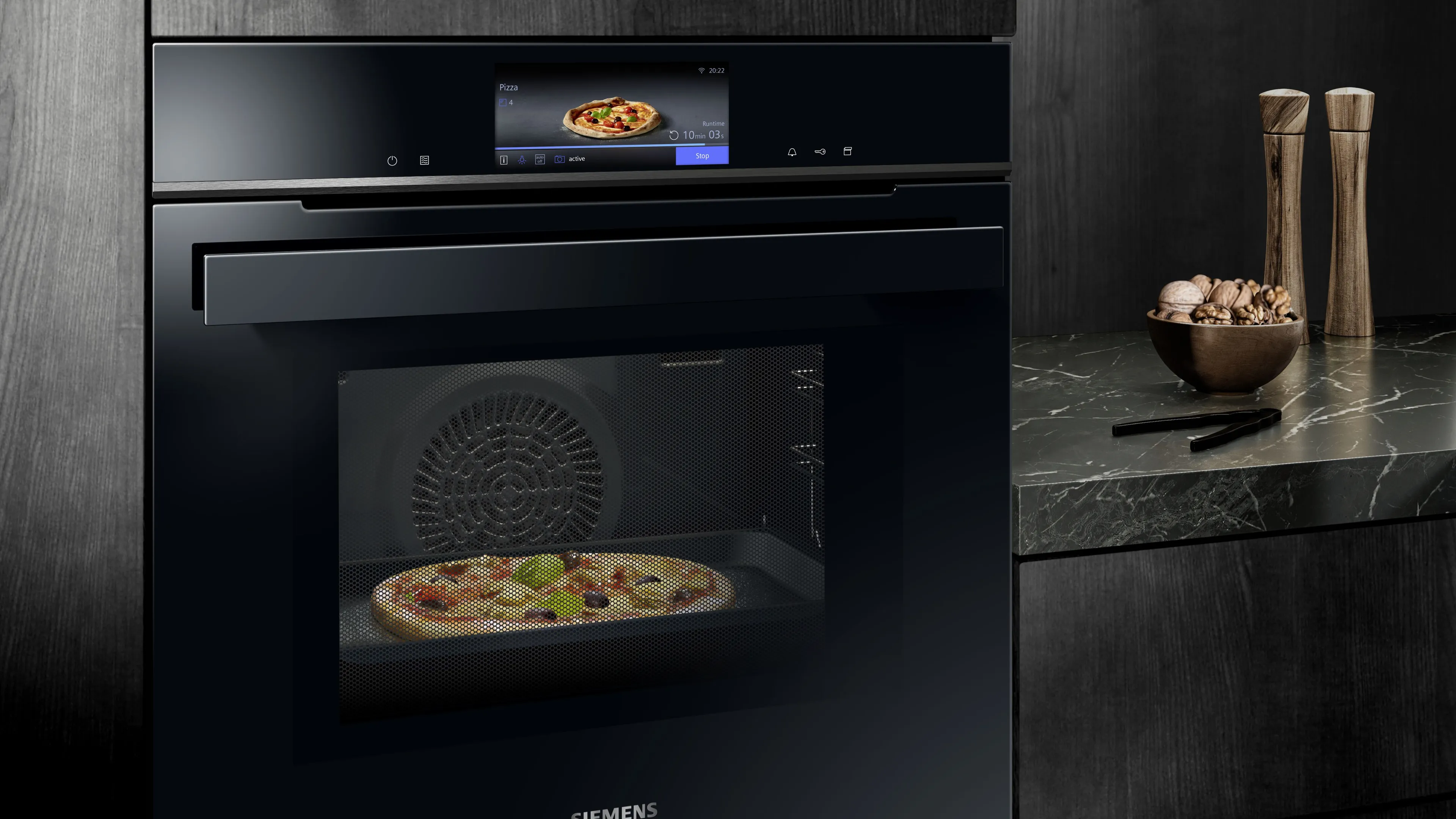 Forno nero con pizza interna, contatore cucina con utensili da cucina, design minimalista.