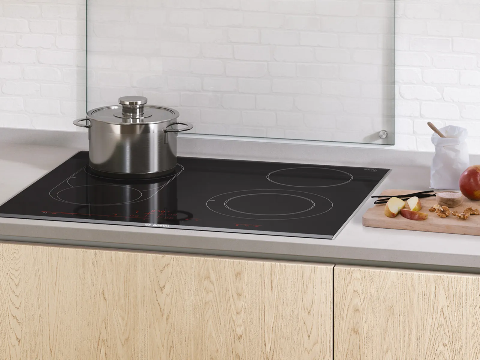 Cuisine moderne avec plateau à induction, pot en acier inoxydable et comptoir en bois.