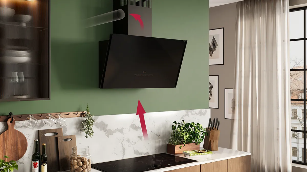 Modern kitchen with green walls, black cooker hood mounted on the wall, marble countertop, and potted plants.