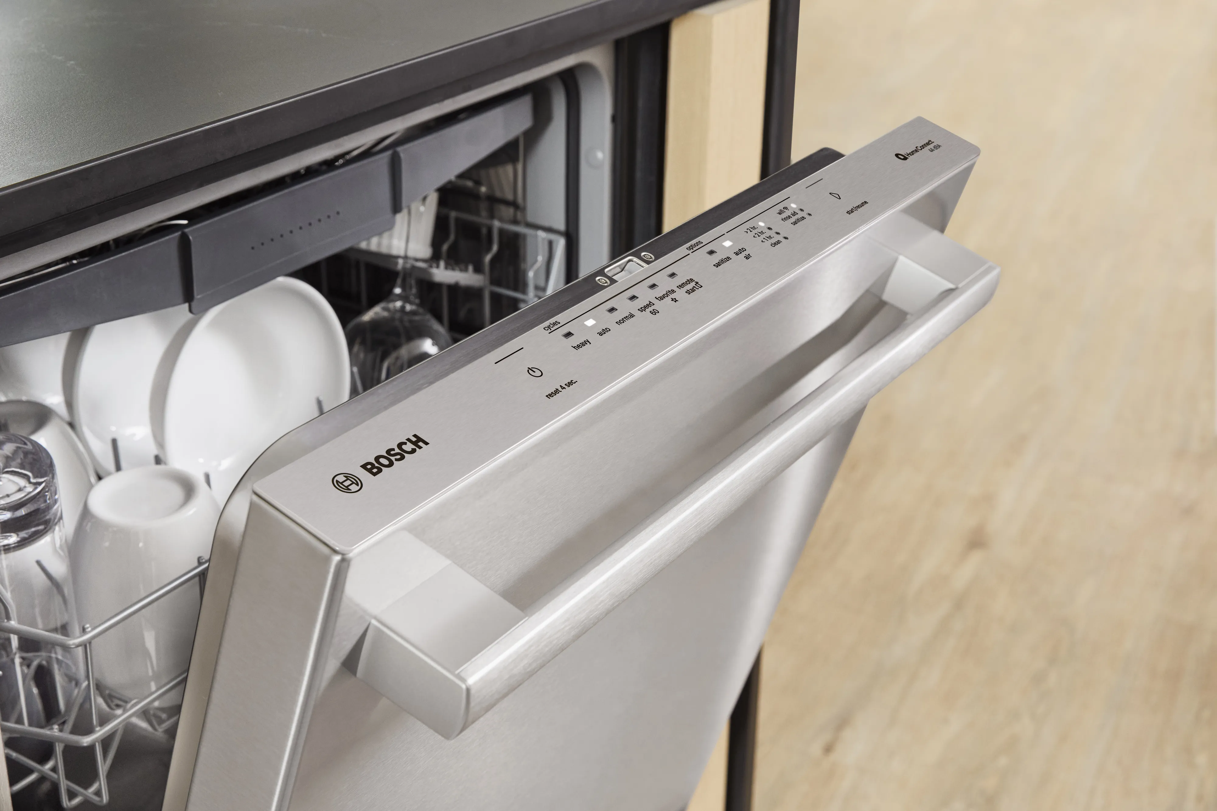 Bosch dishwasher with open door showing dishes inside, sleek control panel visible.