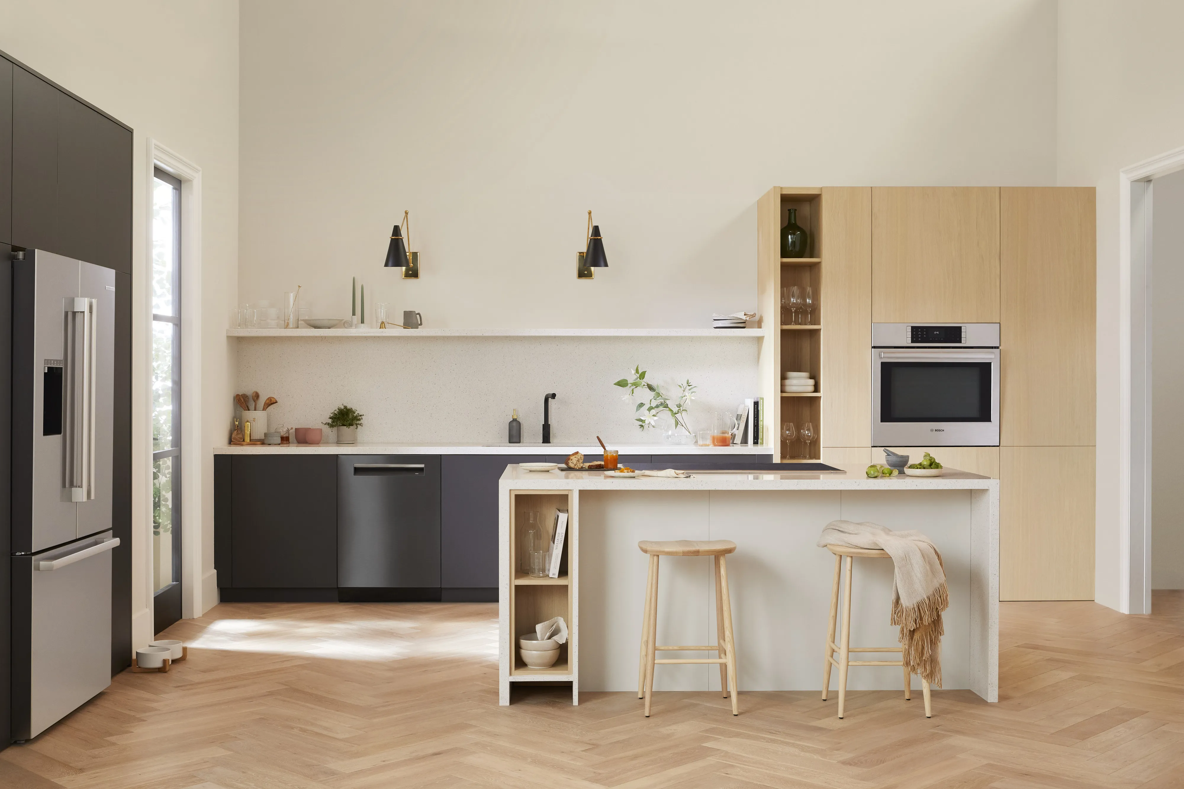 Modern kitchen with Bosch appliances, black and wood cabinets, island with stools, and built-in oven.