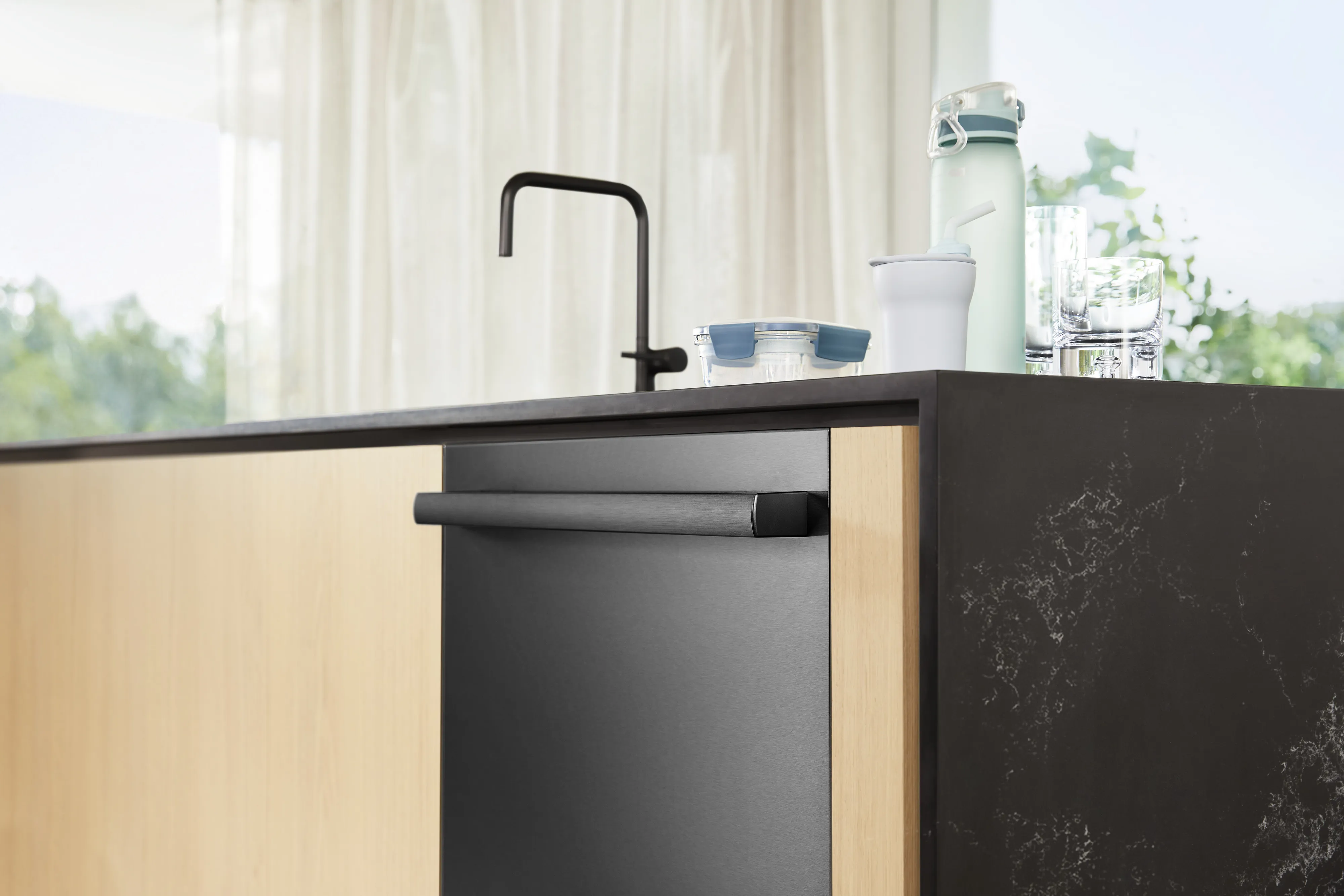 Modern kitchen with a Bosch black & black dishwasher and a sleek faucet on a marble countertop.