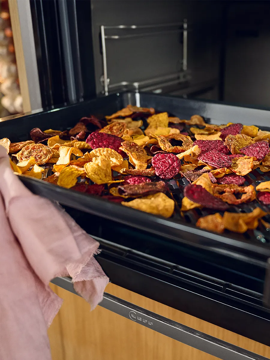 Gebackenes Wurzelgemüse, einschließlich Karotten, Rüben und Kartoffeln, auf einem Backblech im Ofen angeordnet.