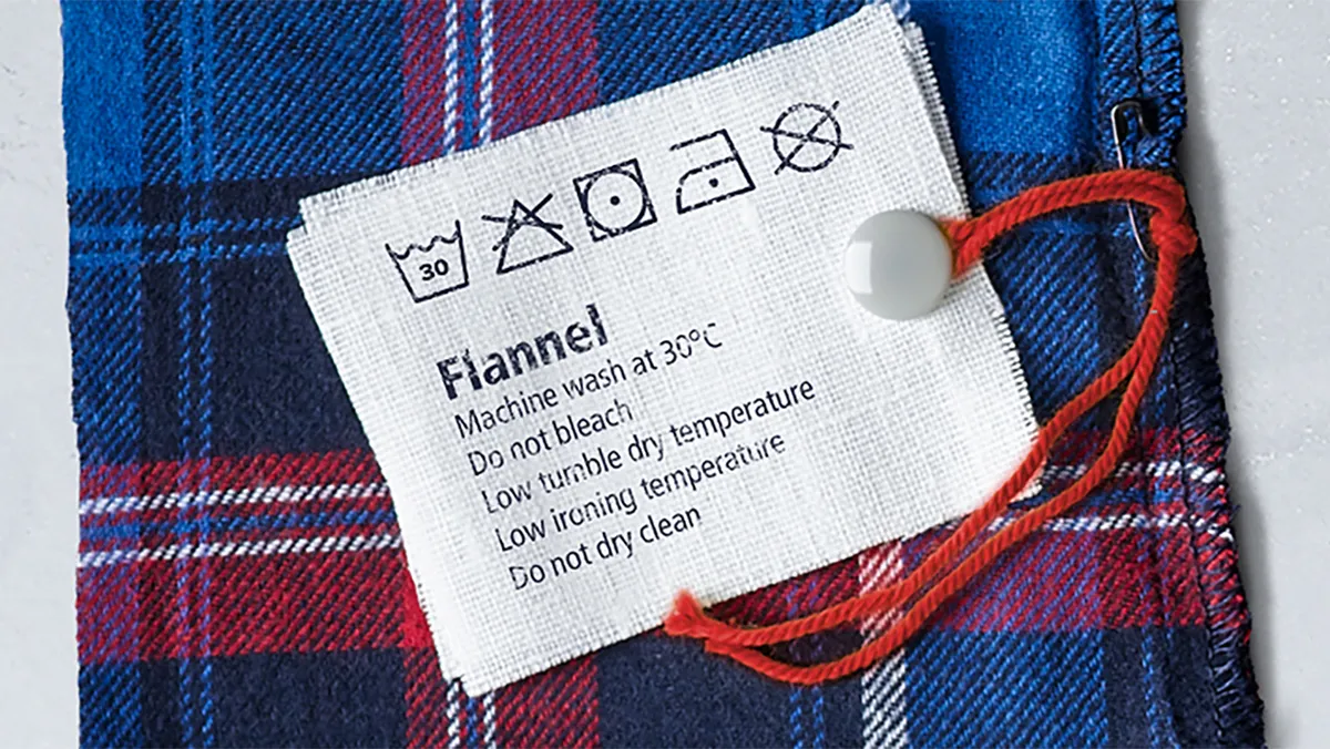 Plaid flannel shirt with care label instructions in text.