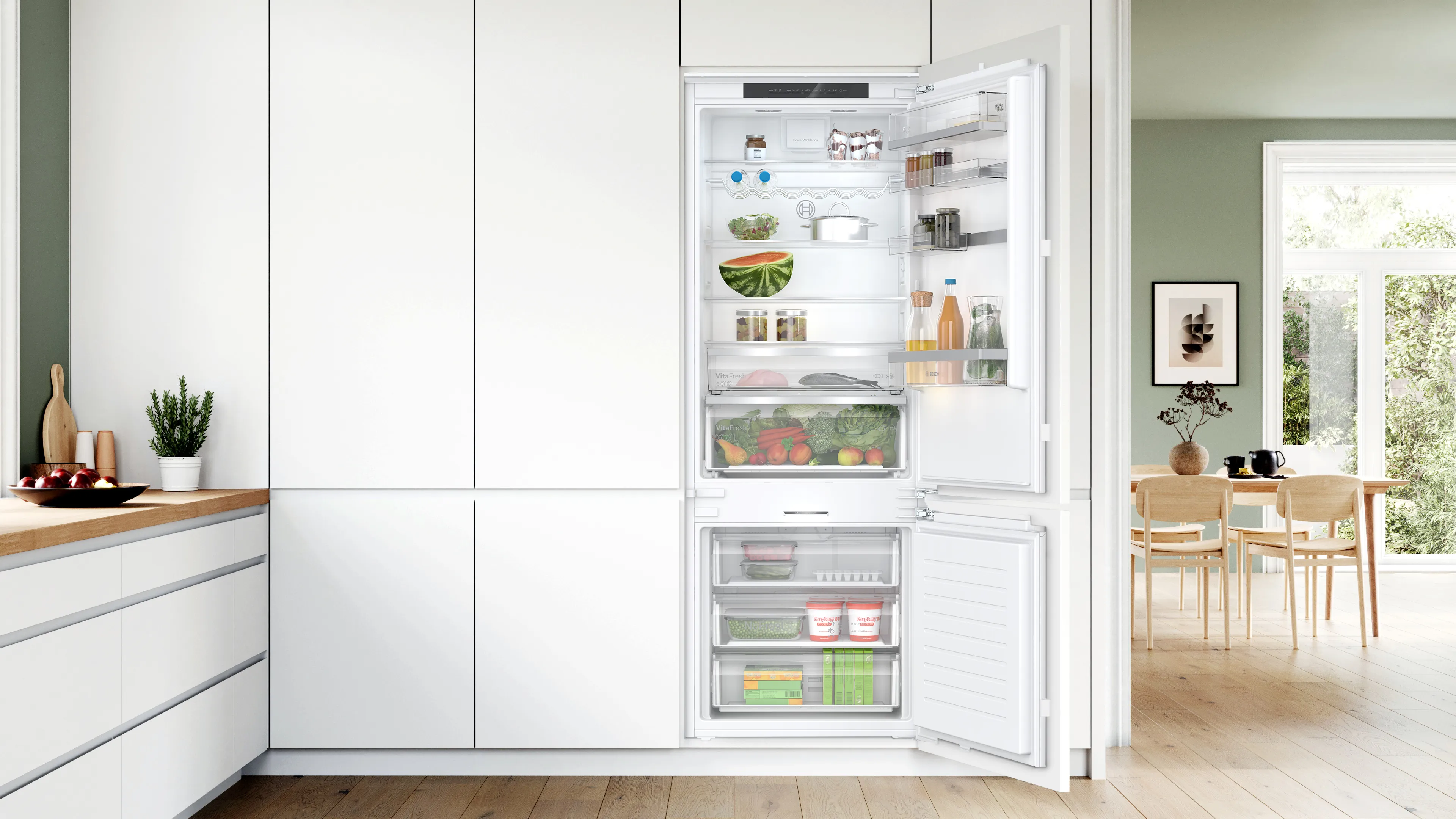 Cucina moderna con frigorifero aperto che mostra vari articoli di cibo e elettrodomestici da cucina.