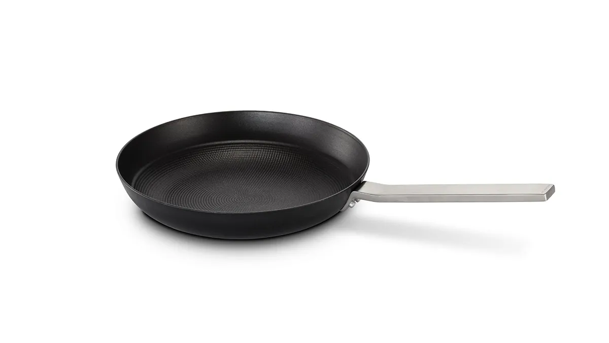 Black non-stick frying pan with metal handle on white background.