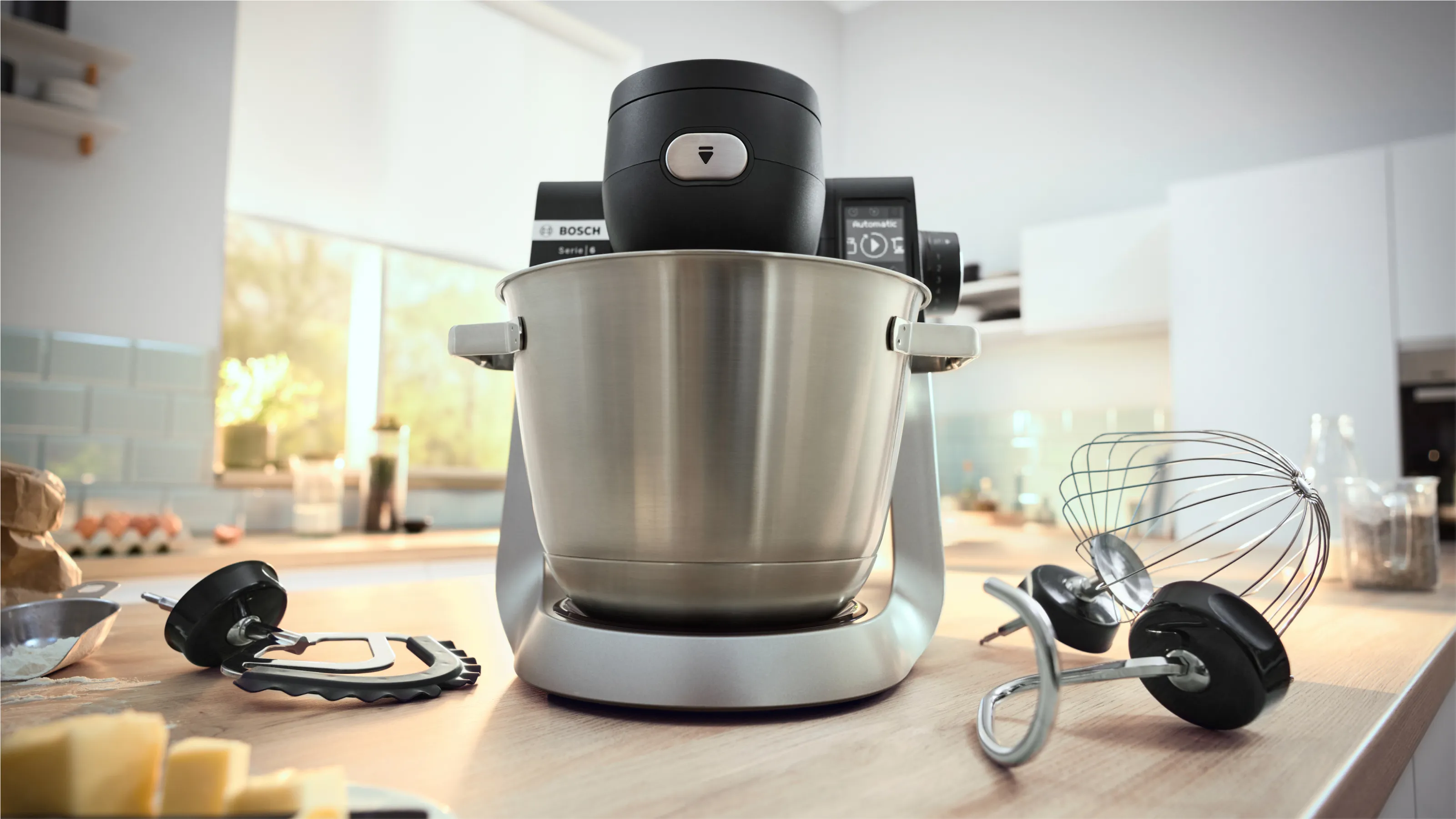Apparecchi da cucina tra cui un mixer stand, frusta e altri utensili da cucina su un piano di lavoro.