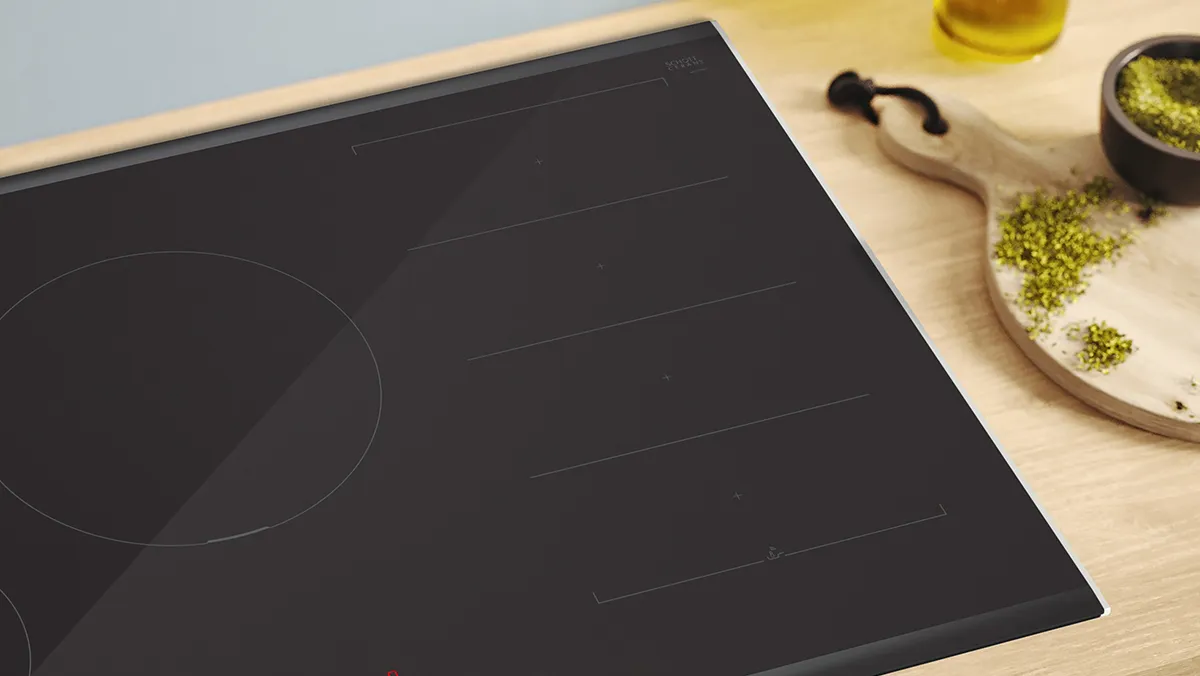 Black induction cooktop, olive oil, herbs, wooden surface, kitchen appliance.