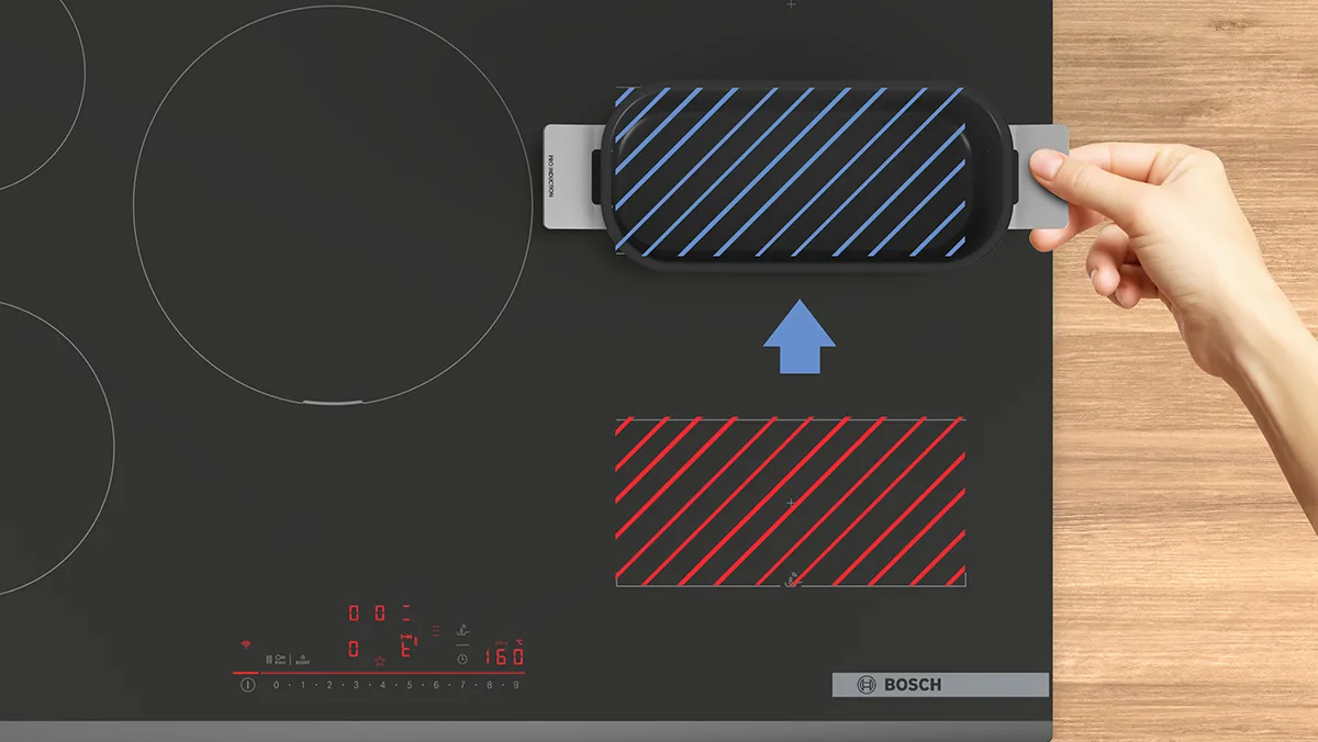 Induction cooktop with control panel, hand holding a blue and white striped USB device.