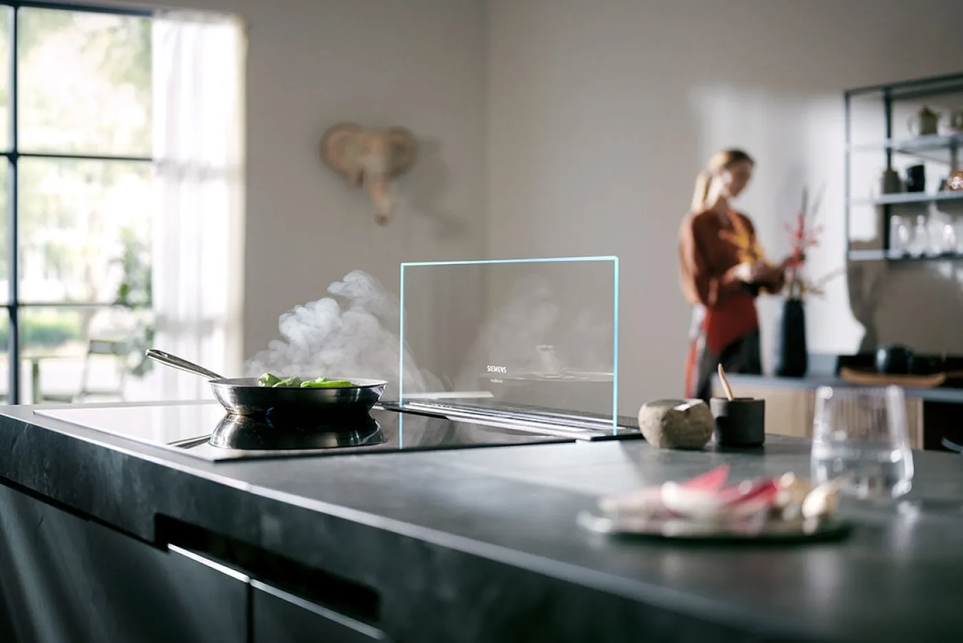 Plano de mujer en una cocina con la placa cocinando
