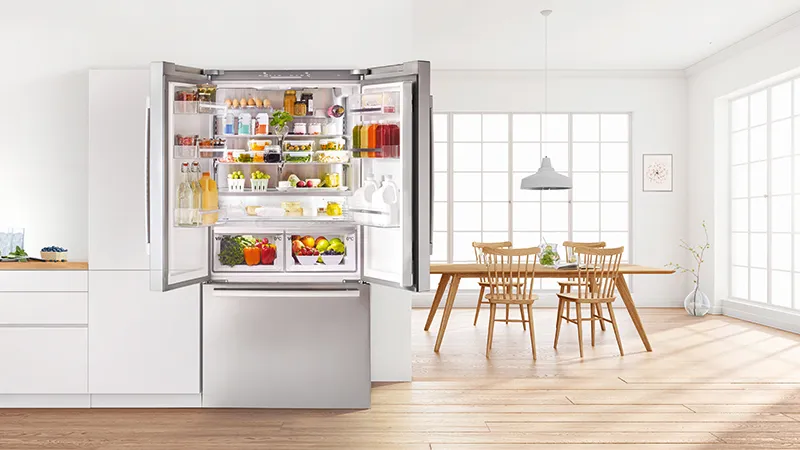 Ampia cucina con frigorifero aperto, tavolo da pranzo e sedie in legno in un interno luminoso e moderno.