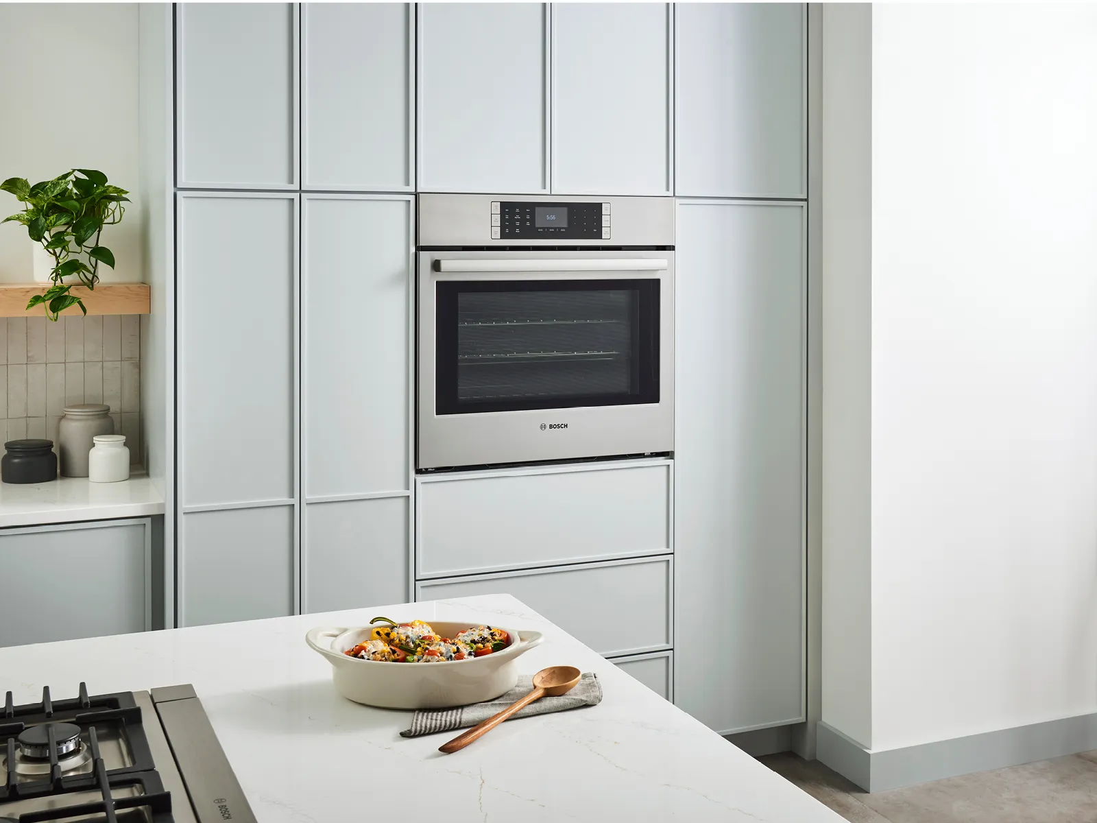Bosch Stainless Steel Built In Wall Oven within mint green kitchen with food on countertop