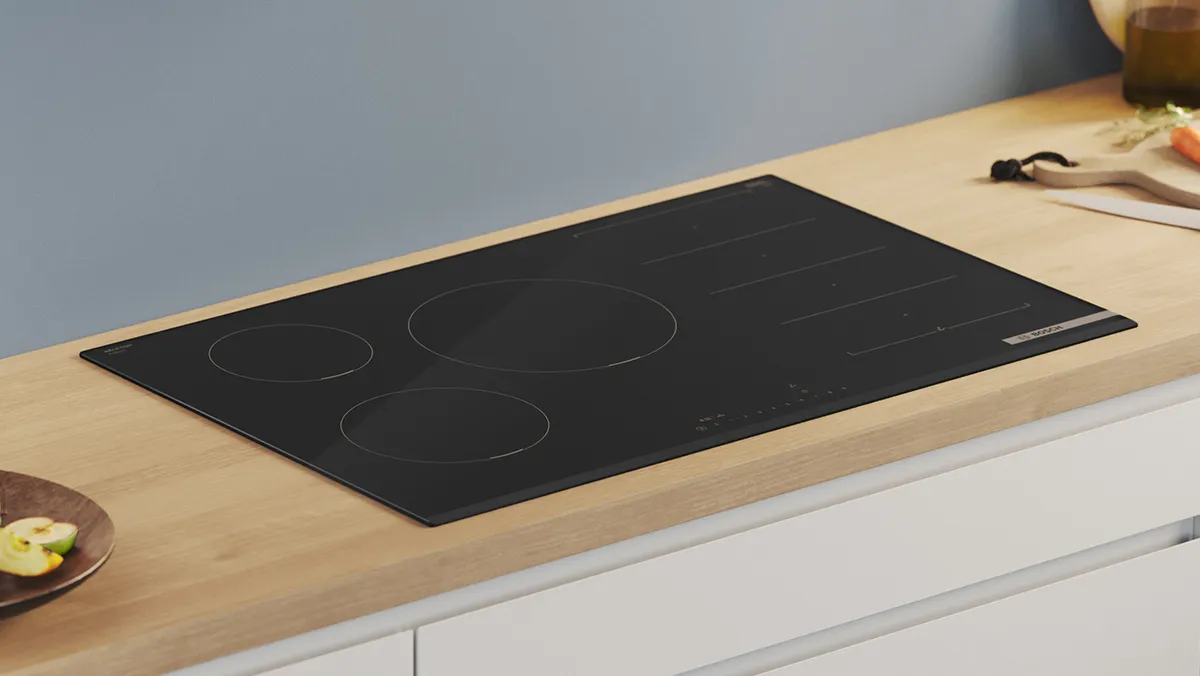 Induction cooktop with three circular cooking zones on a wooden kitchen counter.
